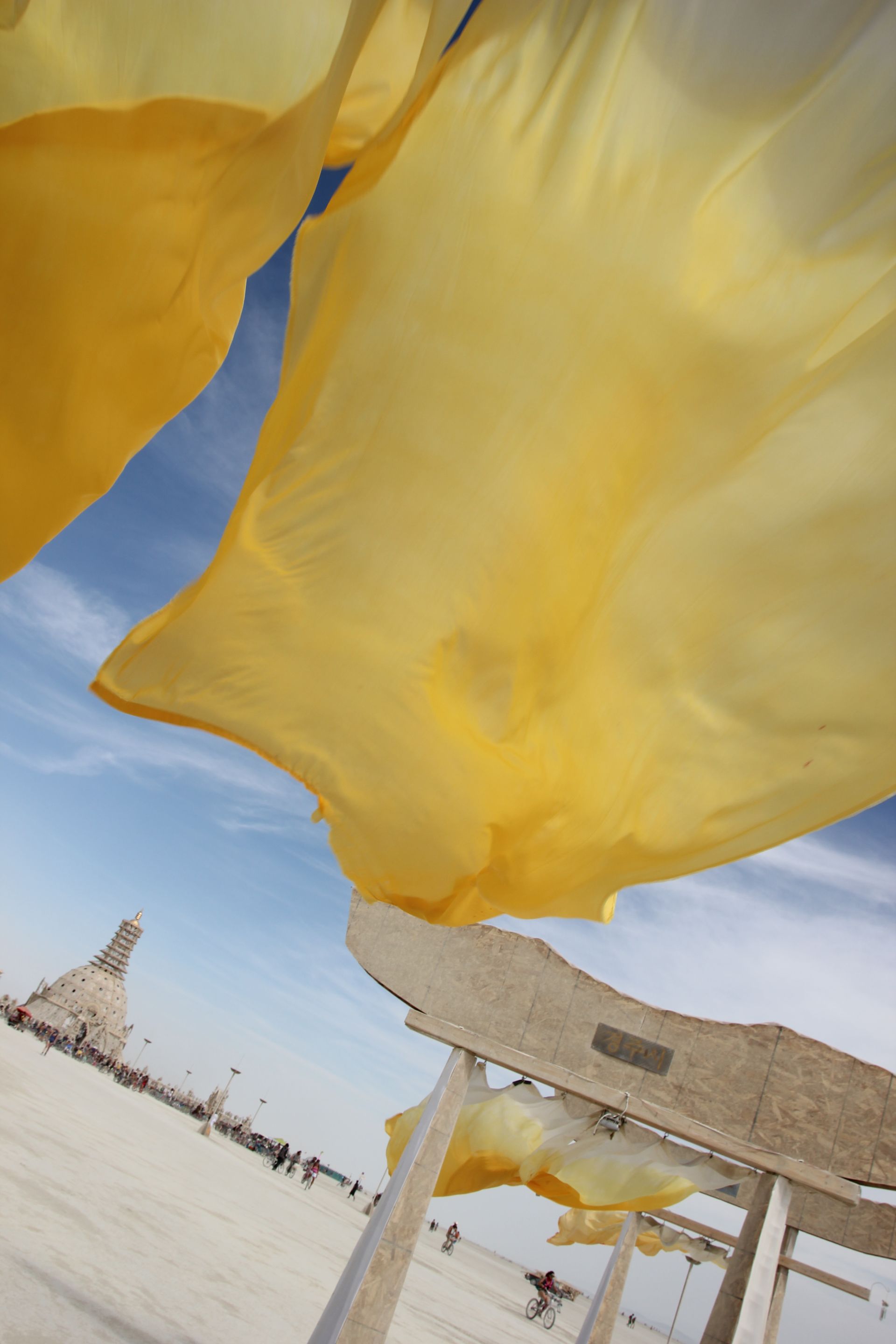 Yellow fabric canopies over a sunny beach lounge area with blue sky in the background