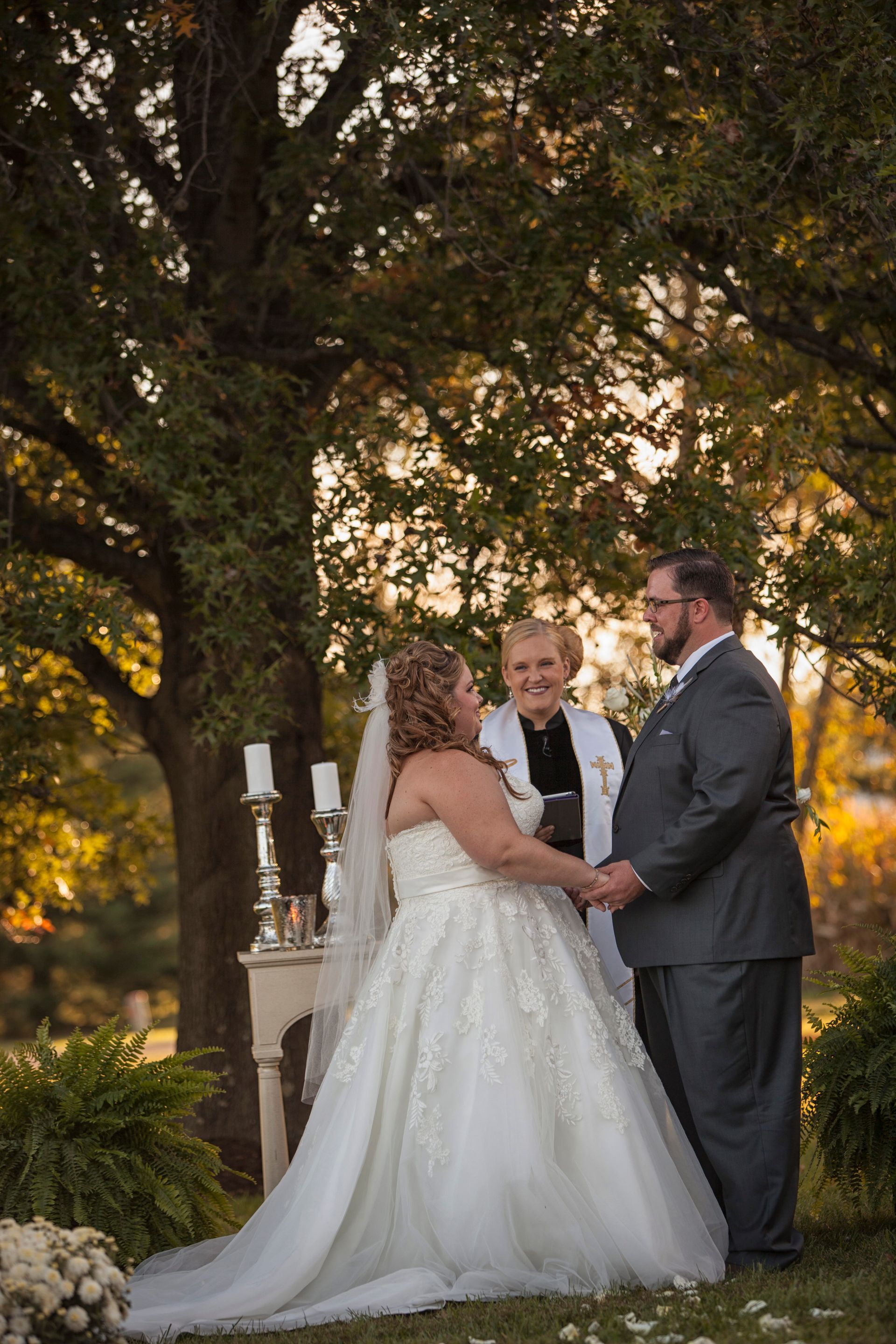 Bride and groom exchanging vows outdoors under trees at a wedding ceremony