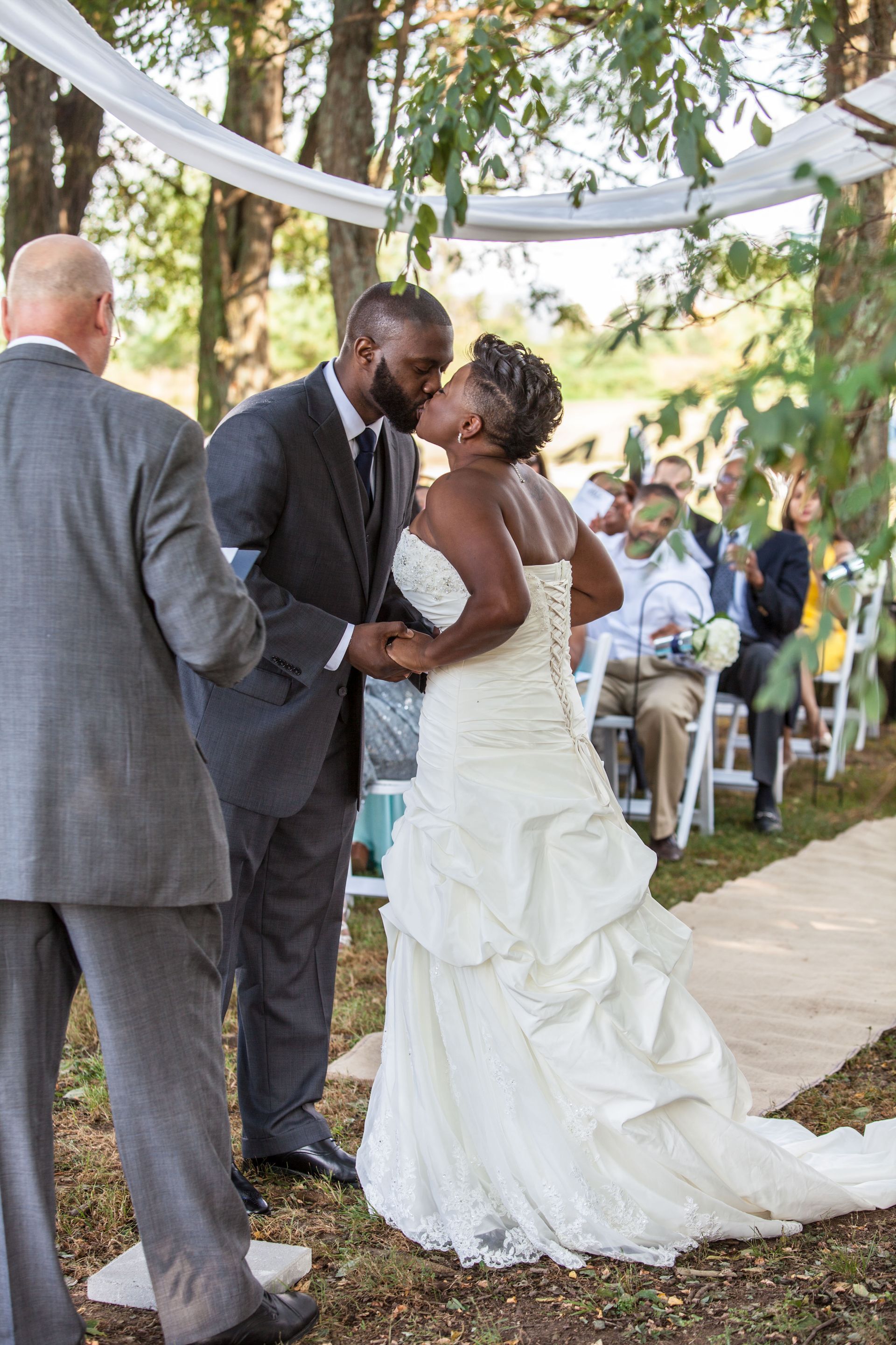 Bride and groom kissing at an outdoor wedding under a white canopy