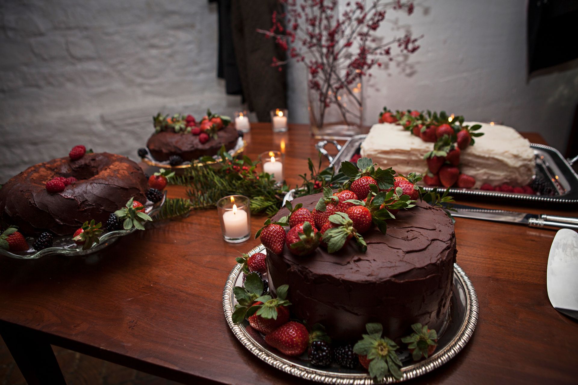 Chocolate cakes and strawberries on a candlelit dessert table for a festive celebration