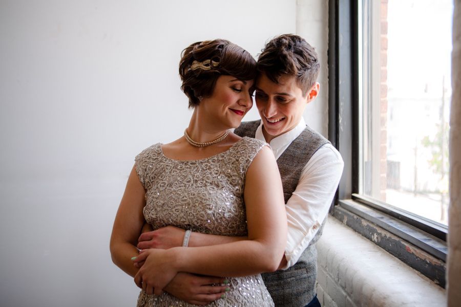 Two people embracing by a window, smiling warmly in soft natural light.