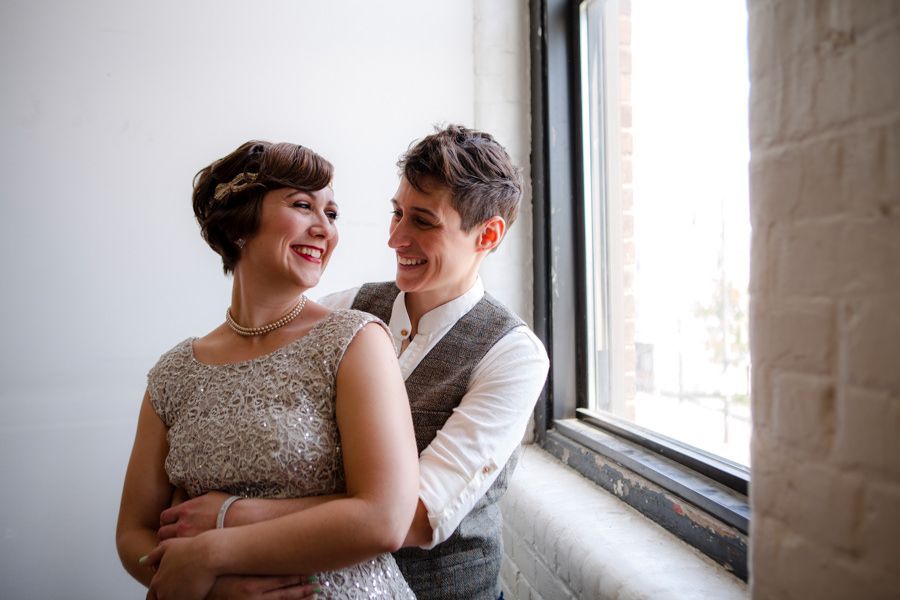 Two people smiling and embracing by a window in a softly lit room