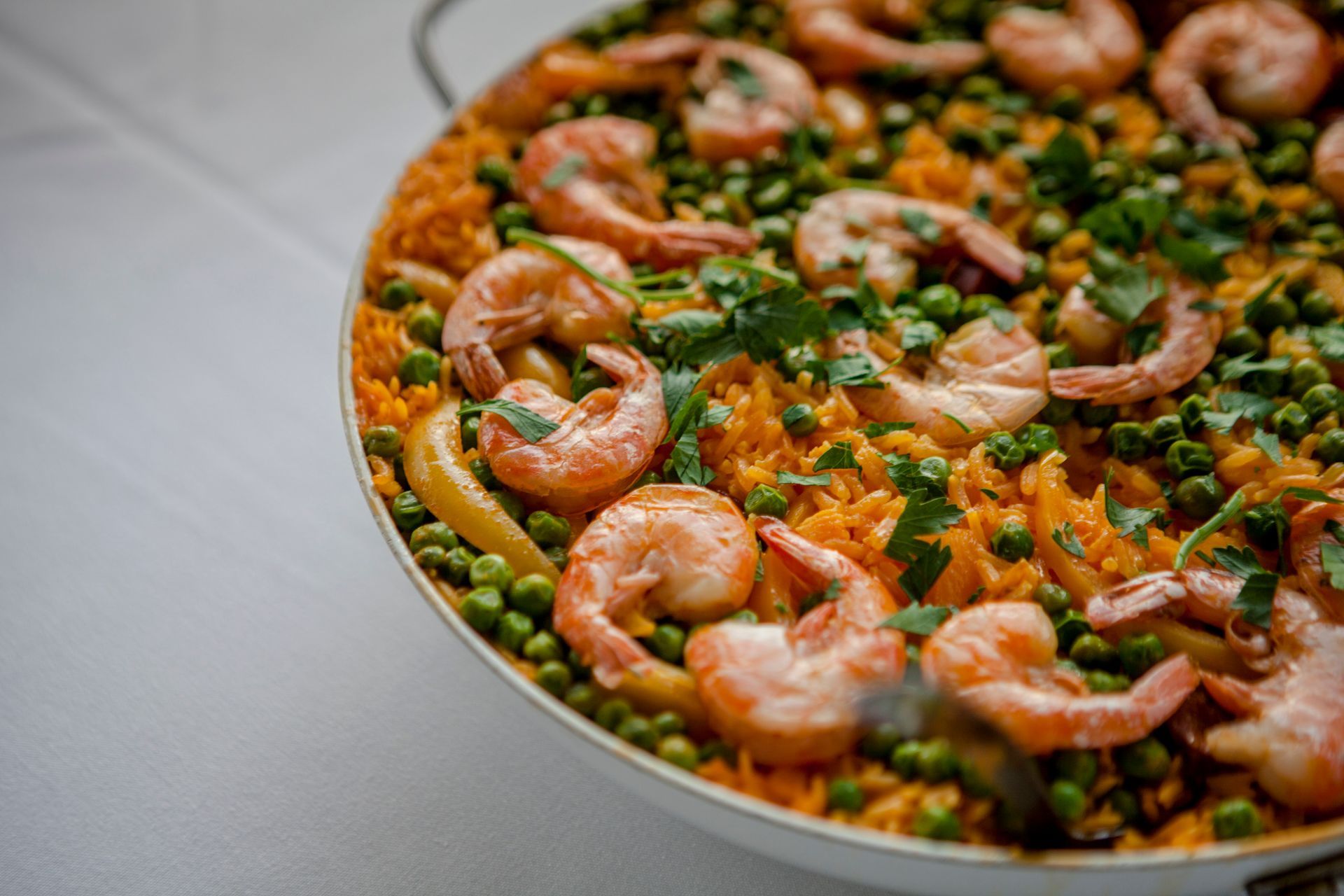 Shrimp and green peas on a pan of rice, garnished with herbs