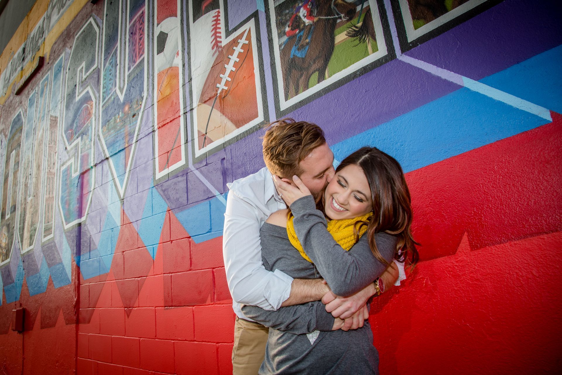 Couple embracing in front of a colorful mural wall