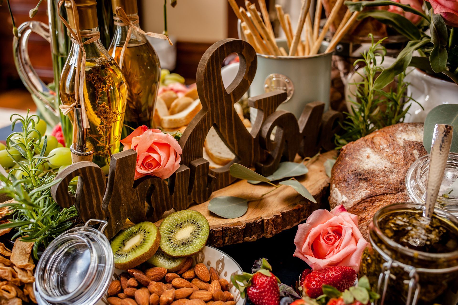Rustic dessert display with fruit, roses, nuts, and a chocolate ampersand centerpiece
