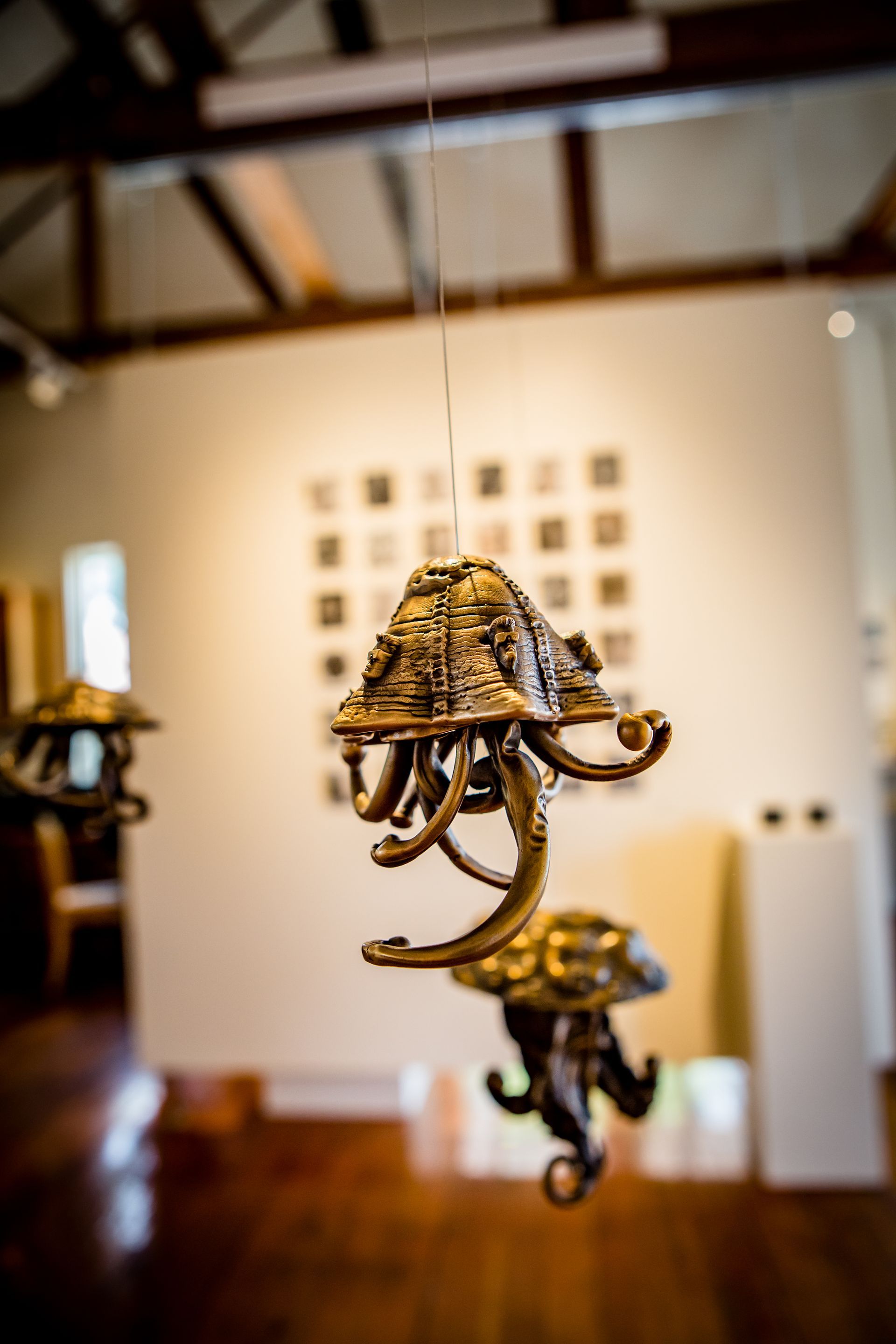 Gold chandelier in a blurred art gallery, with hanging lights and wooden floors in the background
