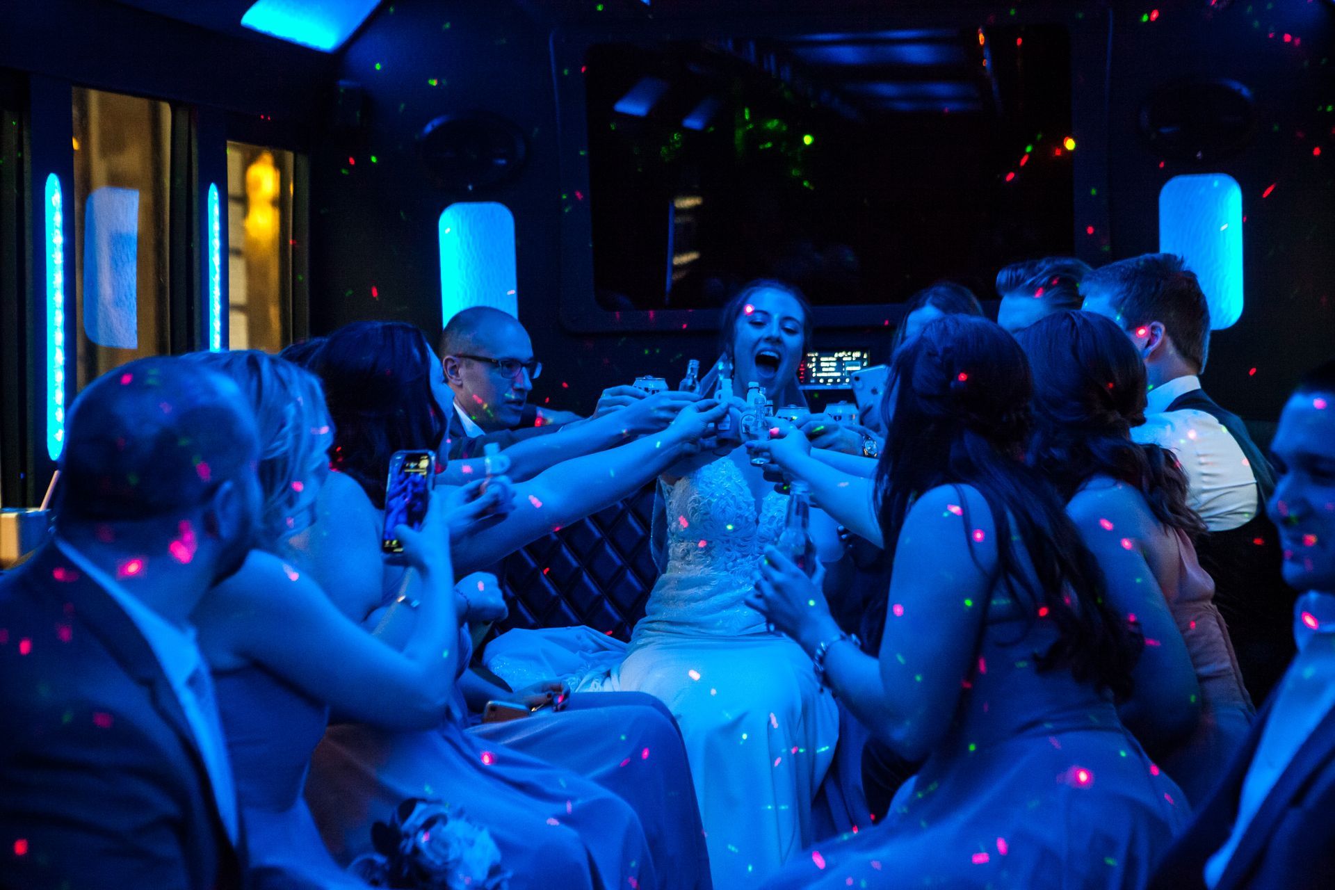People sitting in a blue-lit party scene with pink confetti and drinks, chatting in a lounge.