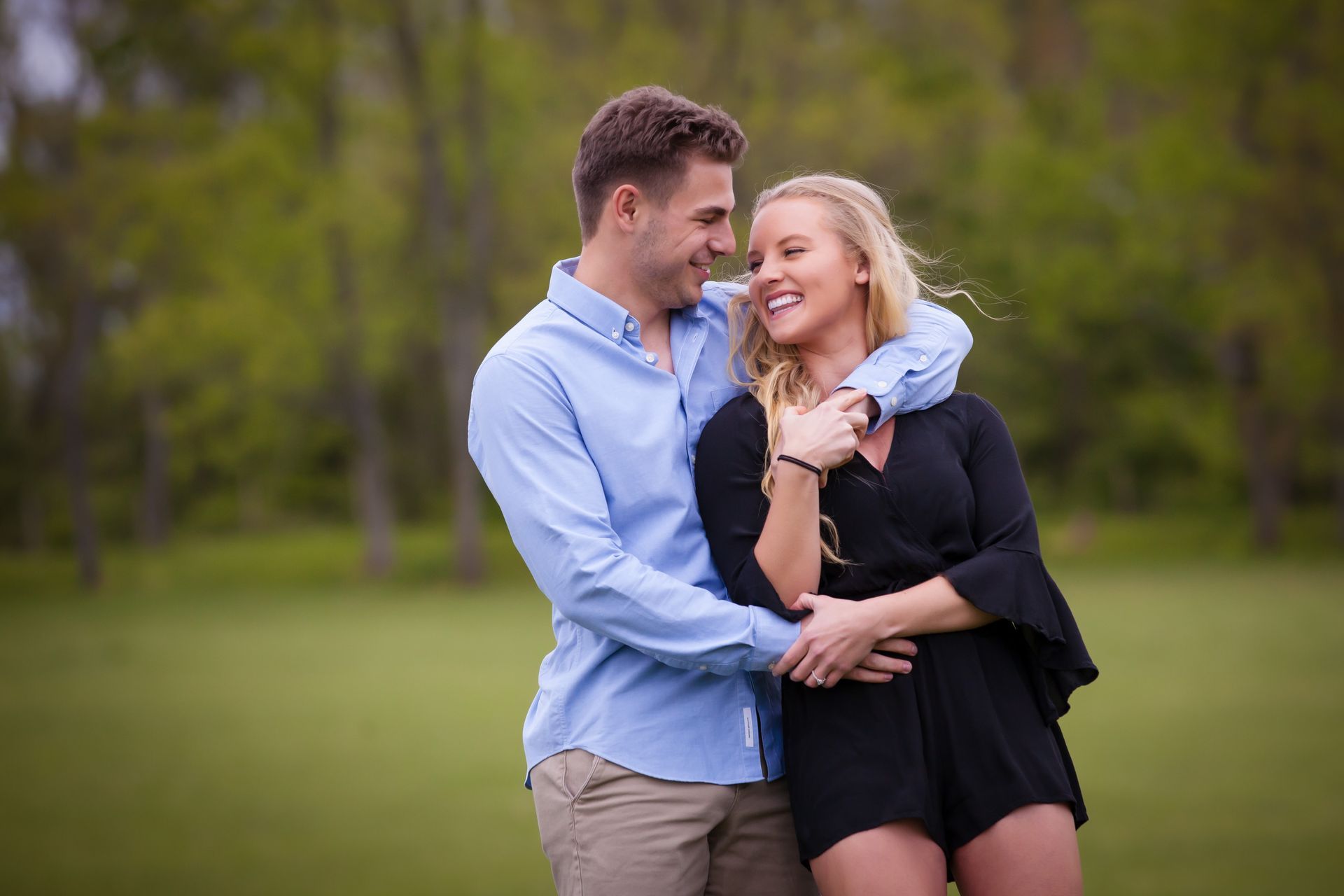 Couple embracing in a green park, smiling and looking at each other.