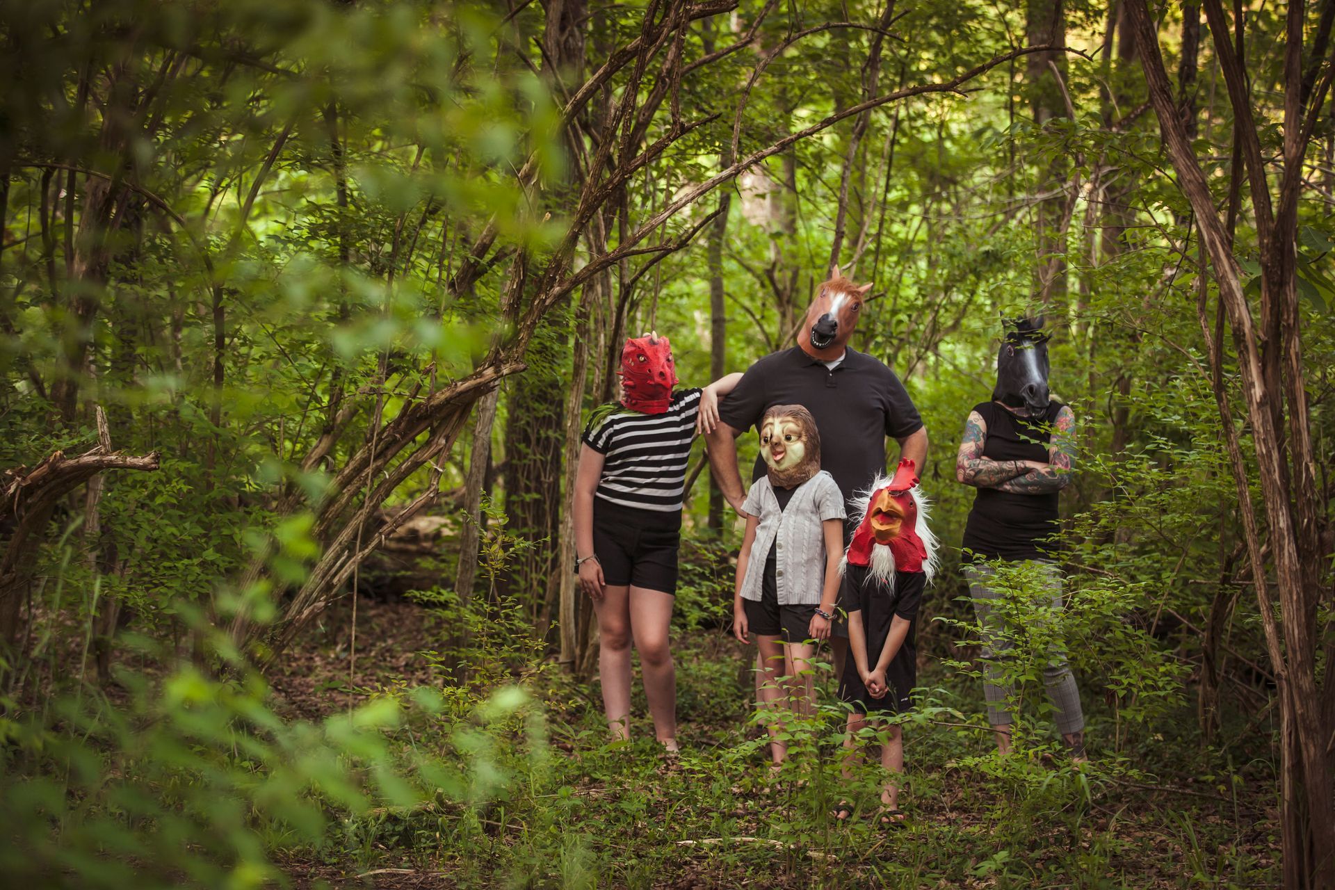 Five people walking through a dense green forest, some carrying backpacks and gear.
