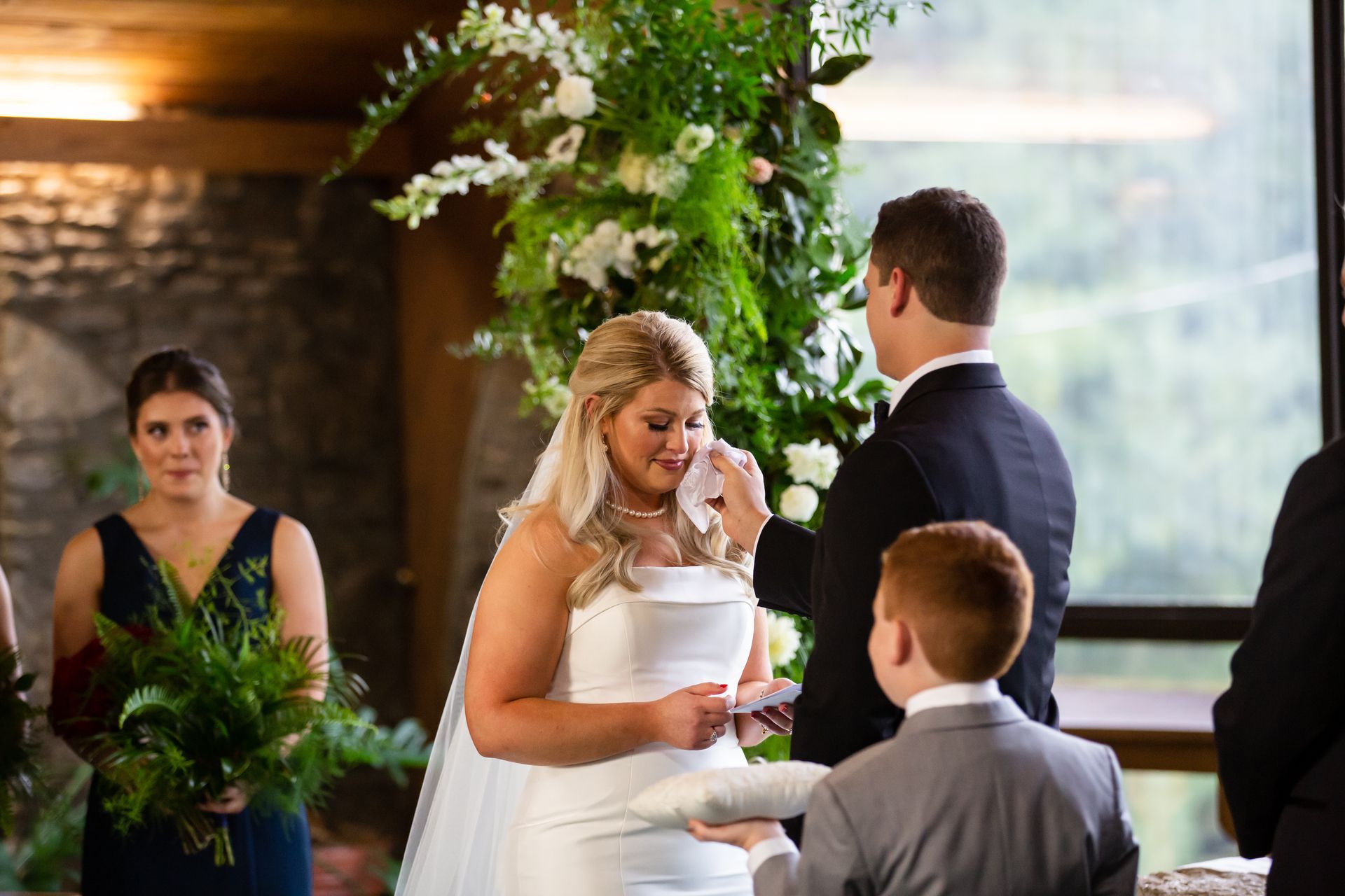 Bride and groom exchanging rings at a wedding ceremony under a floral arch