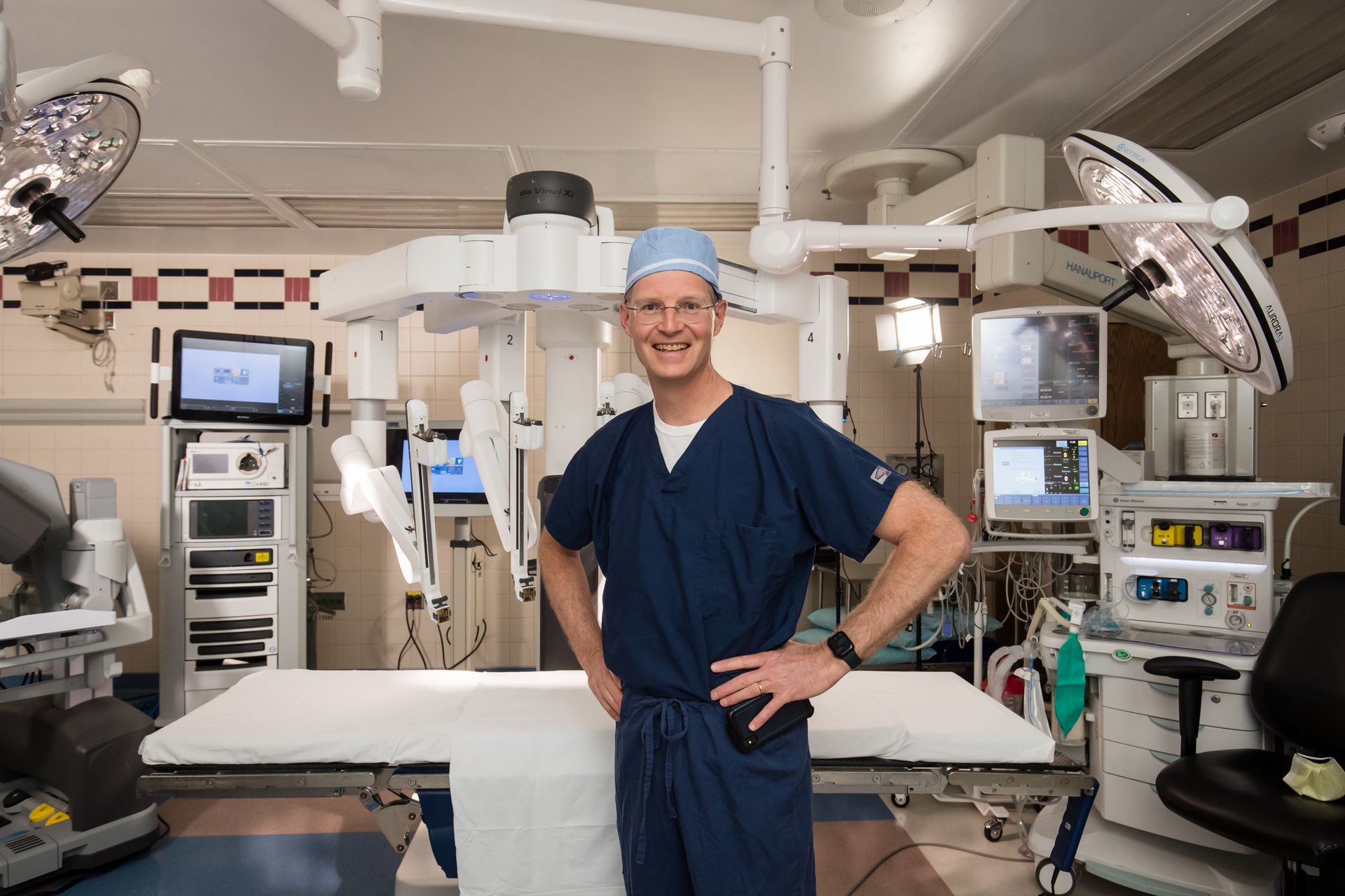 Surgeon in blue scrubs standing in a modern operating room with medical equipment
