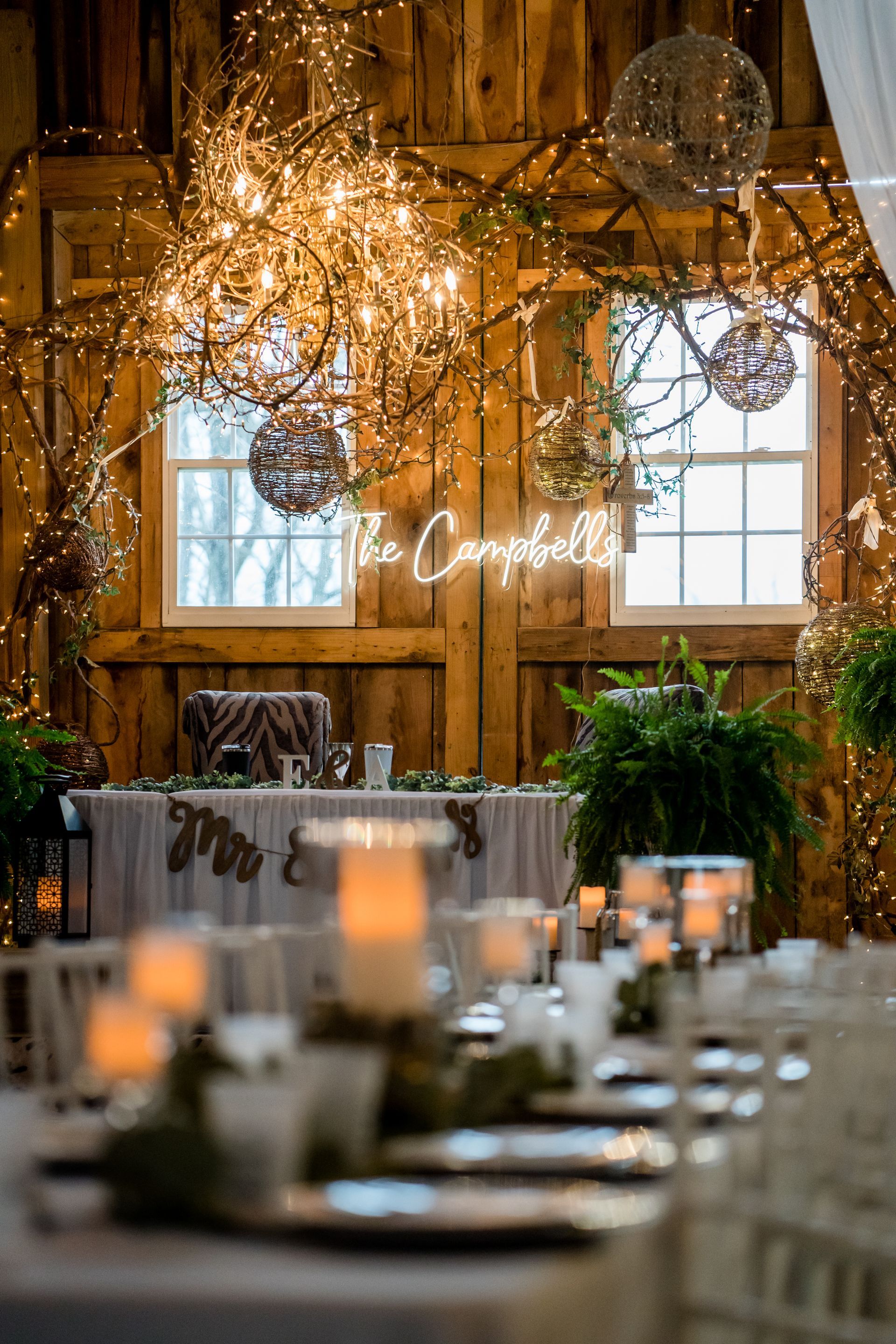 Rustic wedding reception with twinkling lights, candles, and decorated tables in a barn-like venue