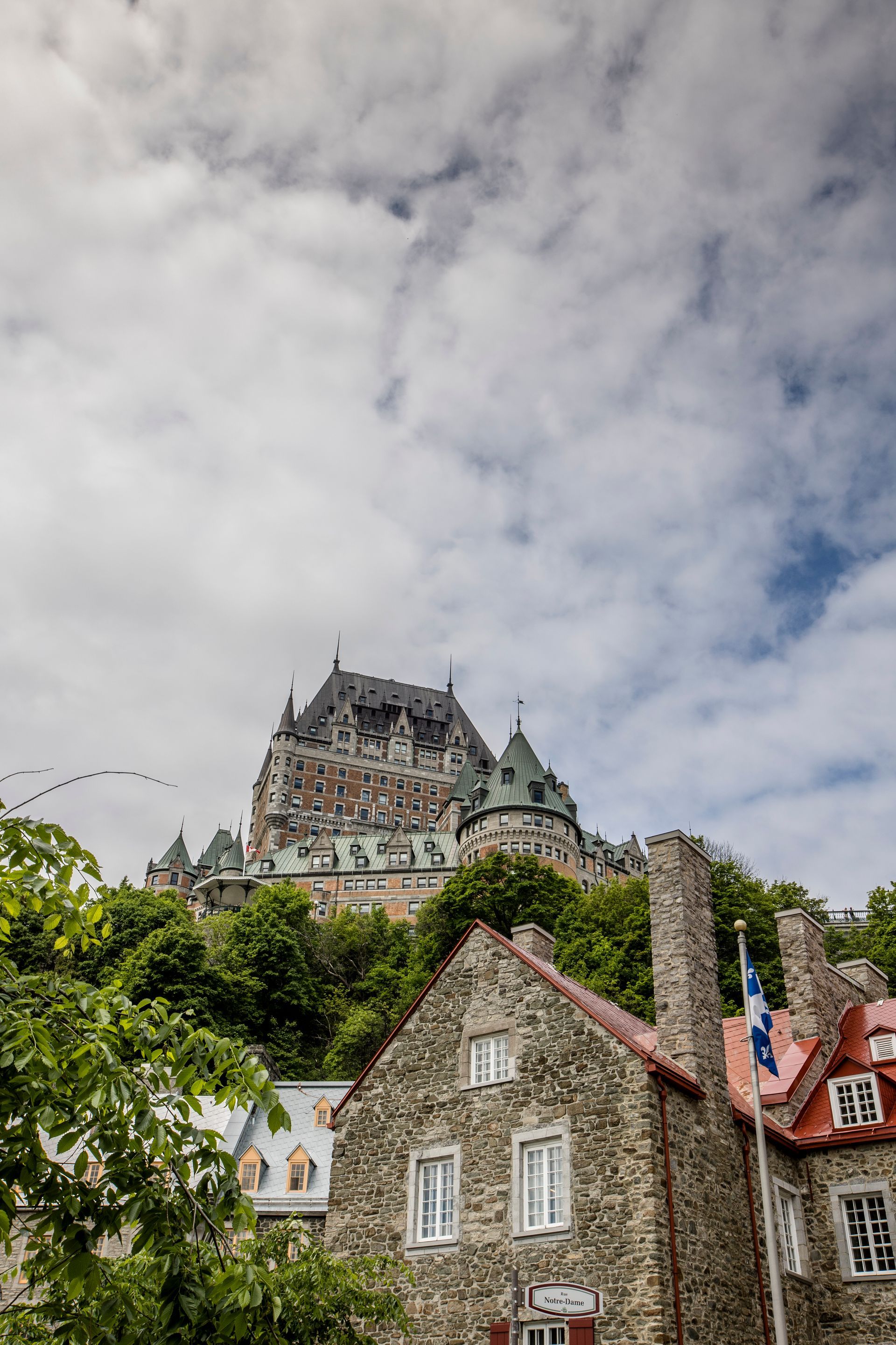 Hilltop stone castle above village rooftops under a cloudy sky