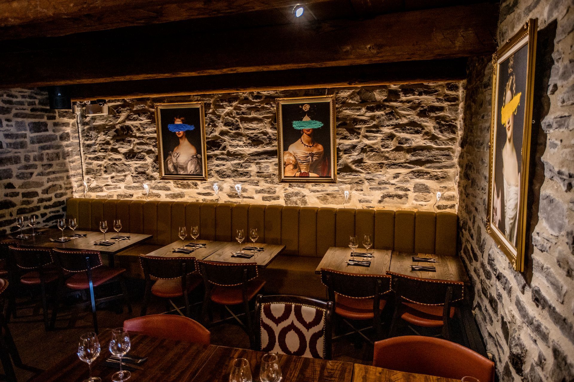 Cozy rustic restaurant interior with stone walls, wood paneling, tables, and framed art on the wall