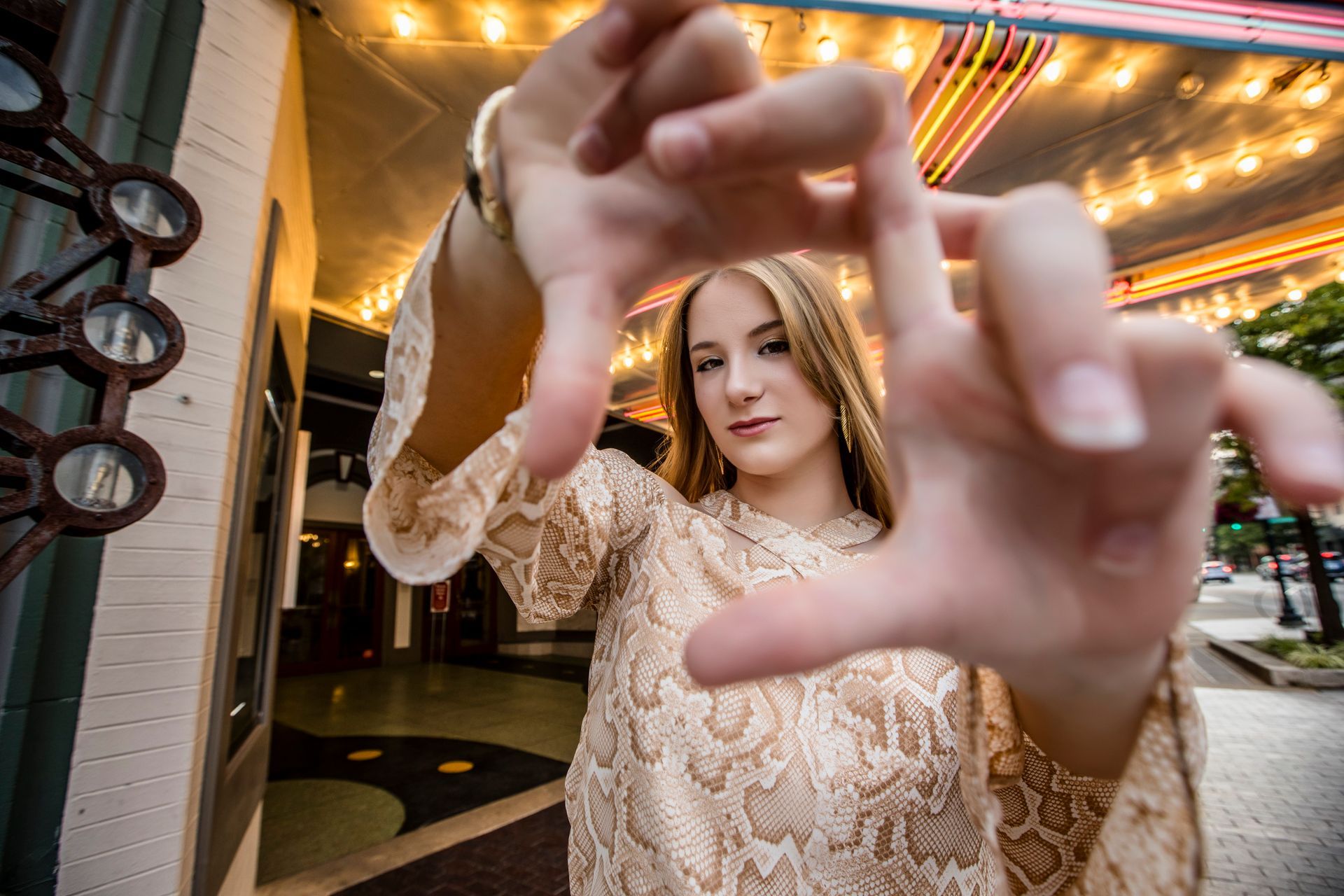 Person in a gold lace dress reaching toward the camera in a warmly lit indoor hallway
