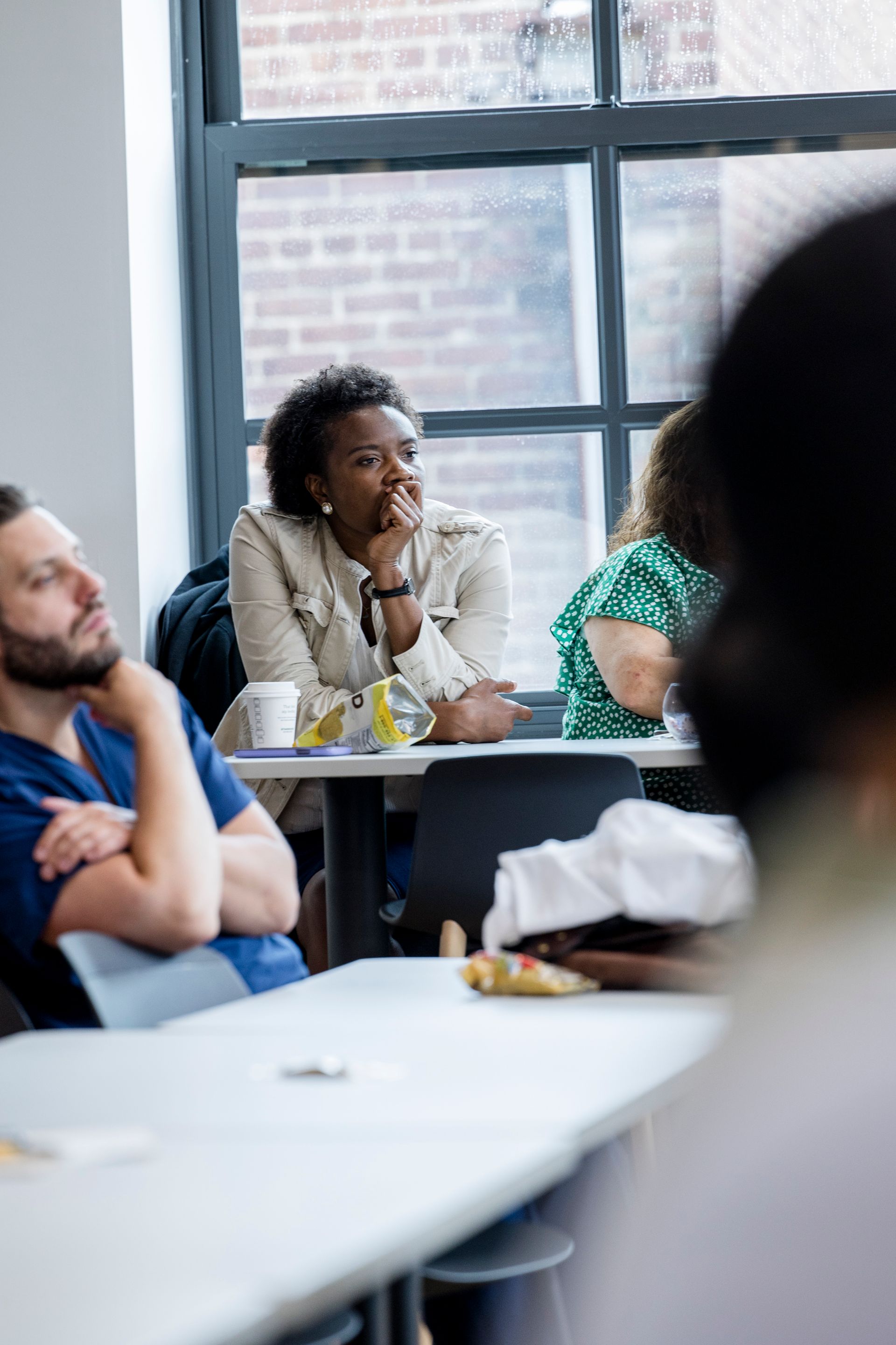 People seated at a table in a bright meeting room, listening attentively.