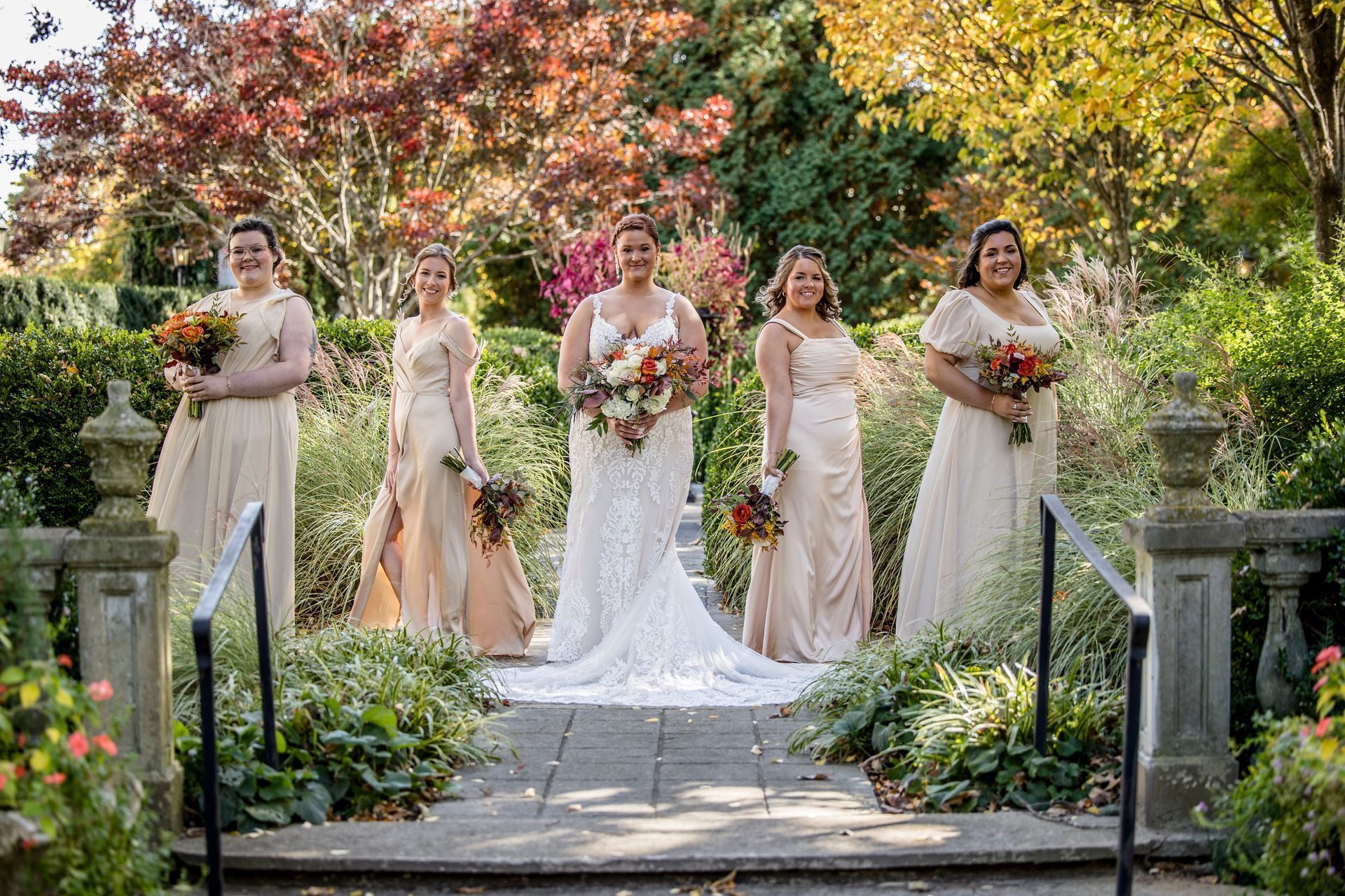 Wedding party posing in a garden walkway with autumn foliage and flowers