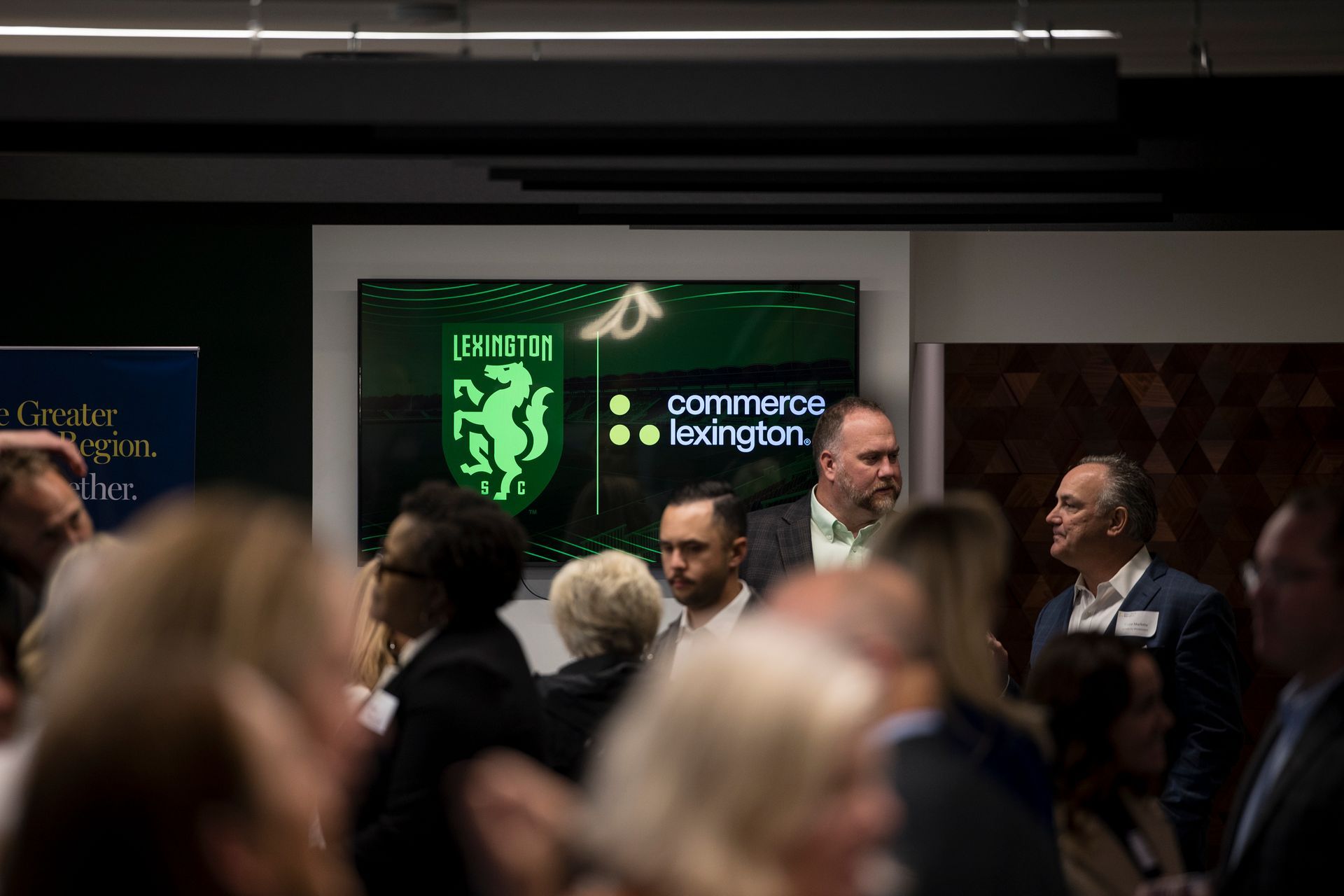 Audience at a conference watching a screen with the Commerce Integration logo and green lion crest