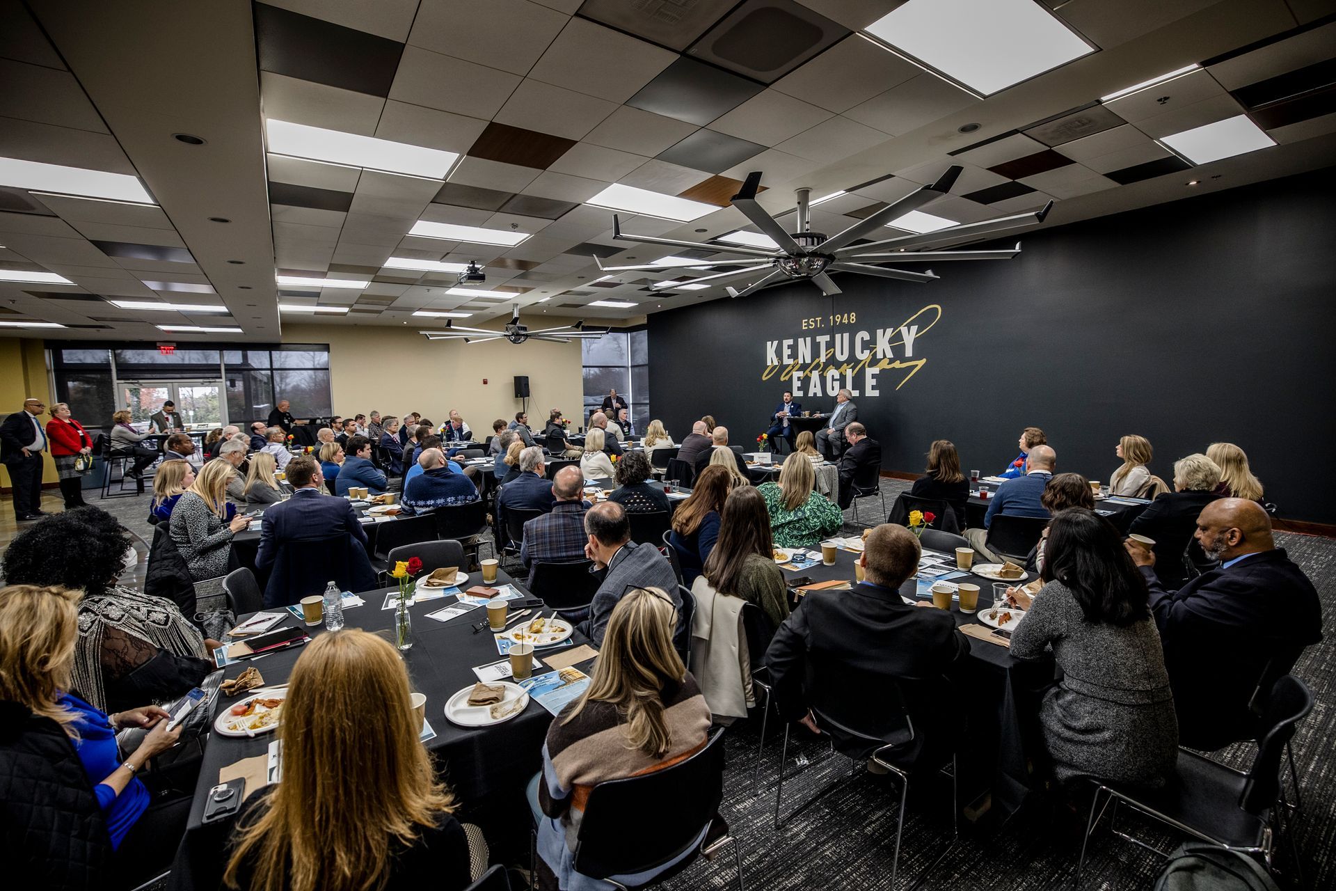 Crowded banquet hall with seated guests and a Rockwell Table event sign on the stage