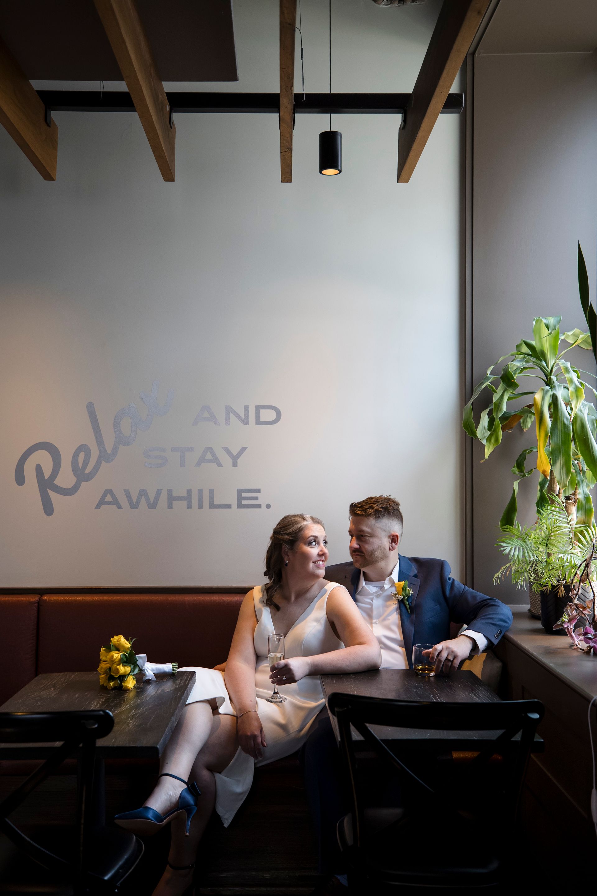 Two people seated at a dimly lit restaurant table beneath wall text and hanging beams