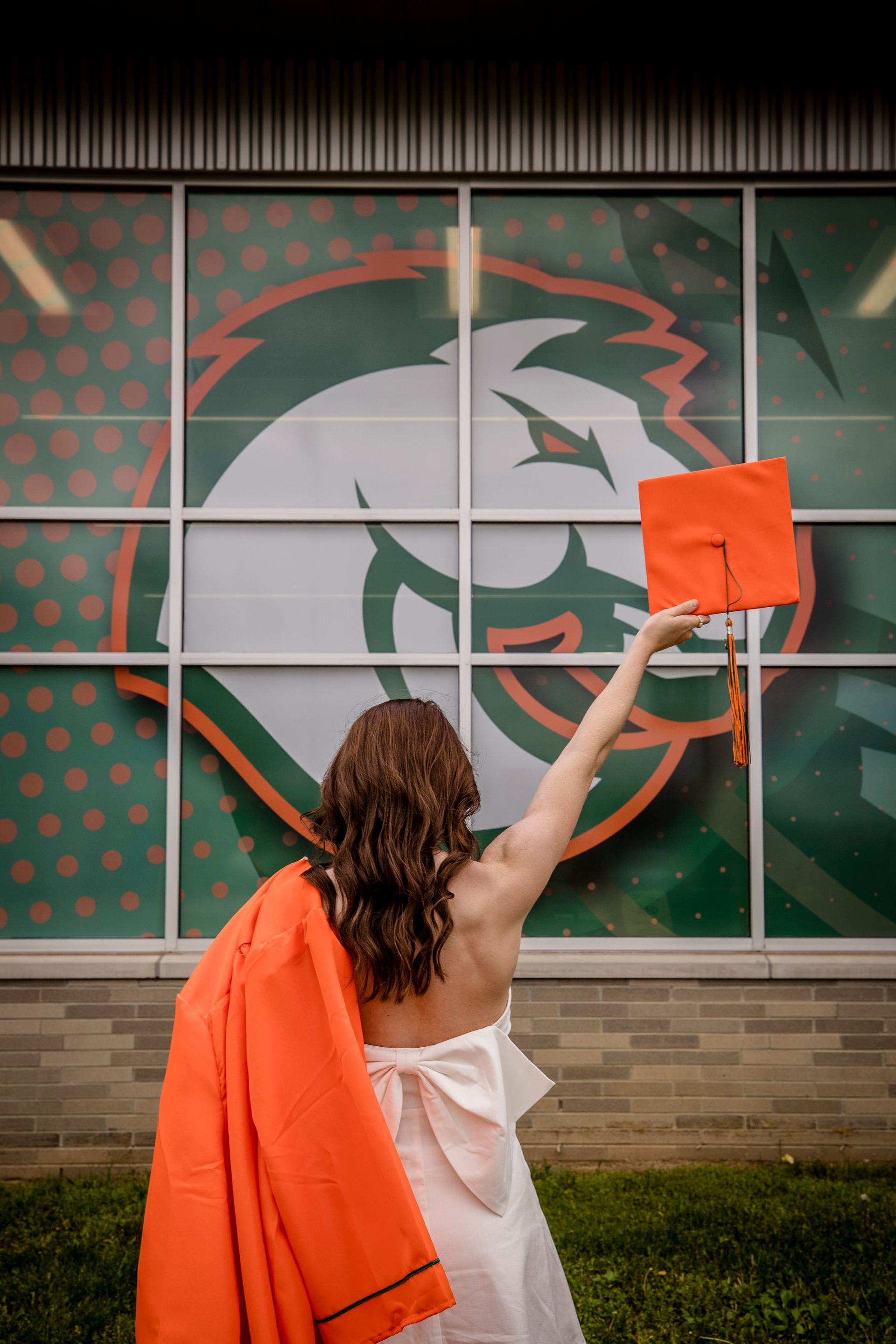 Person holding an orange flag in front of a large bear logo on a building wall