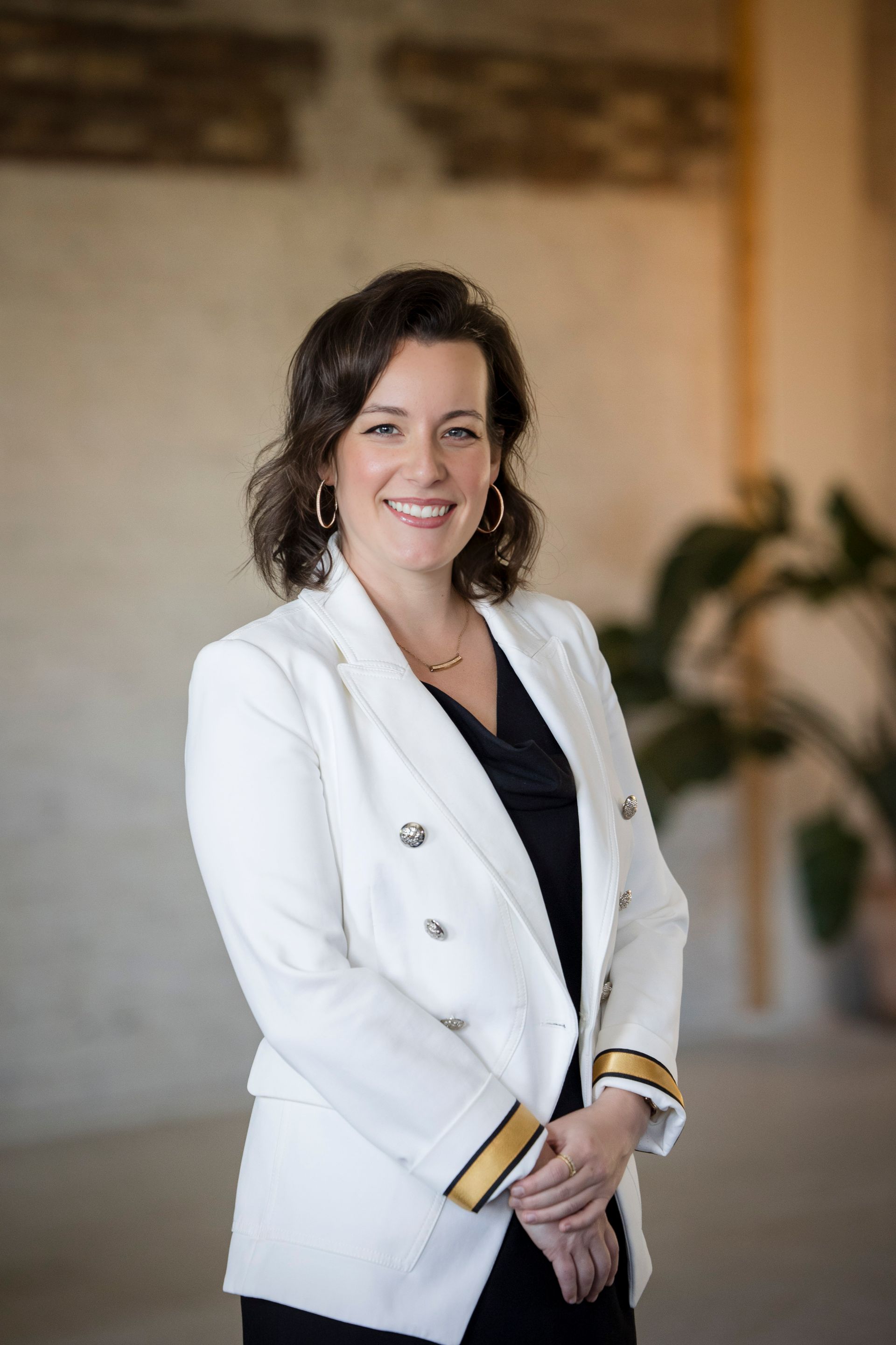 Woman in a white blazer smiling in a softly lit office setting