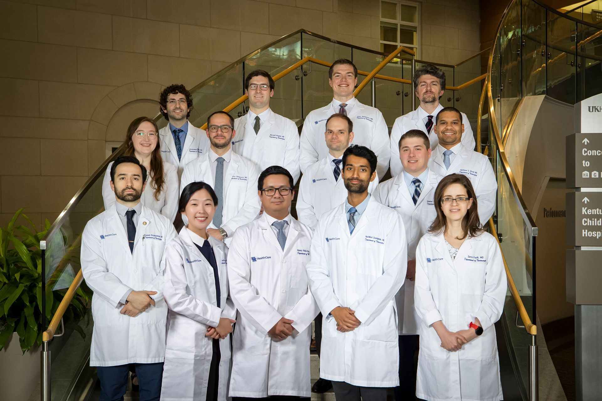 Group of scientists in white lab coats posing on a staircase in a laboratory setting