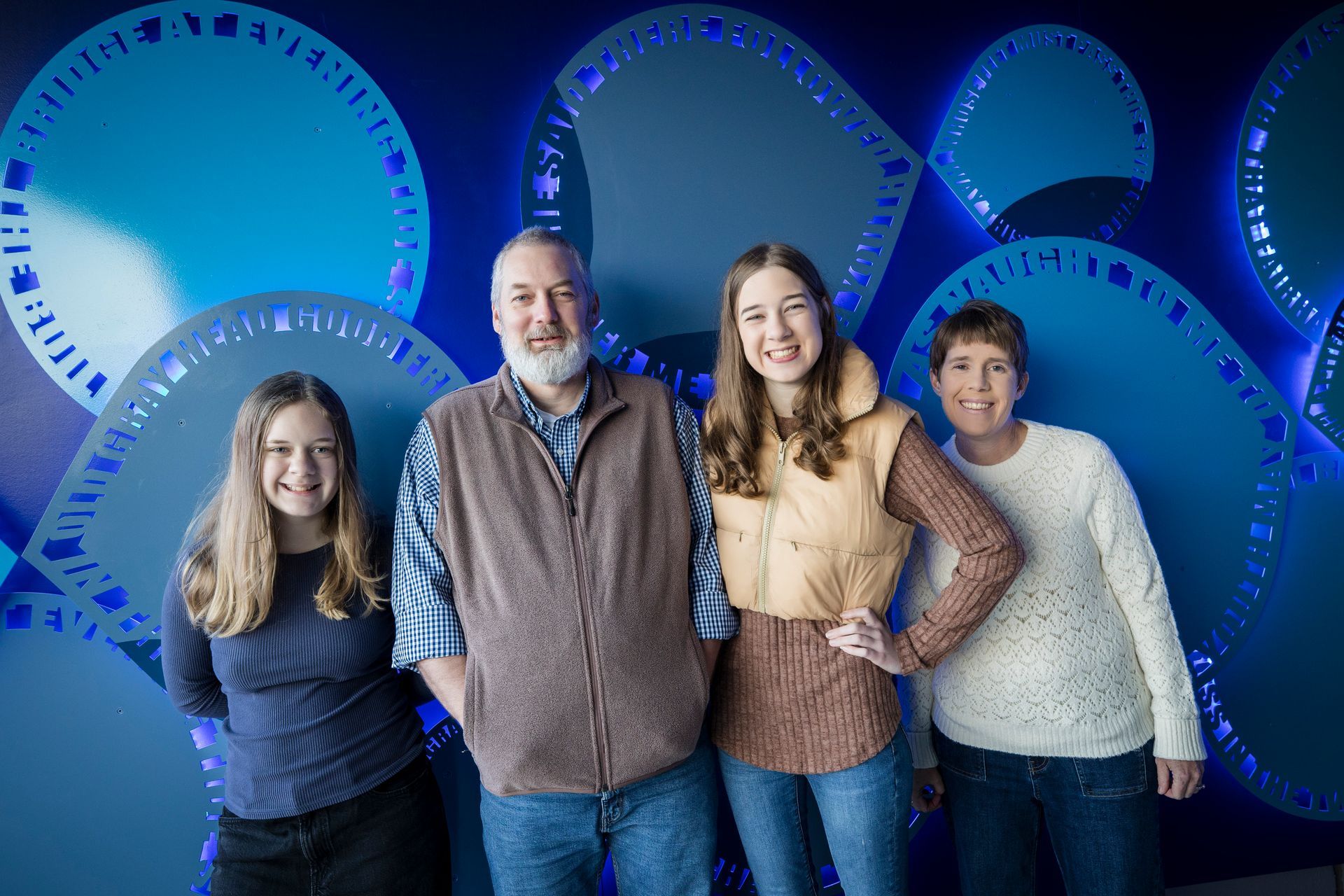 Four people posing together in front of blue circular light sculptures