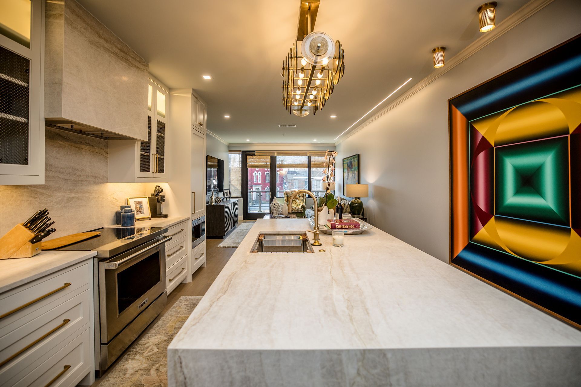 Modern kitchen with white island, chandelier, and colorful geometric wall art