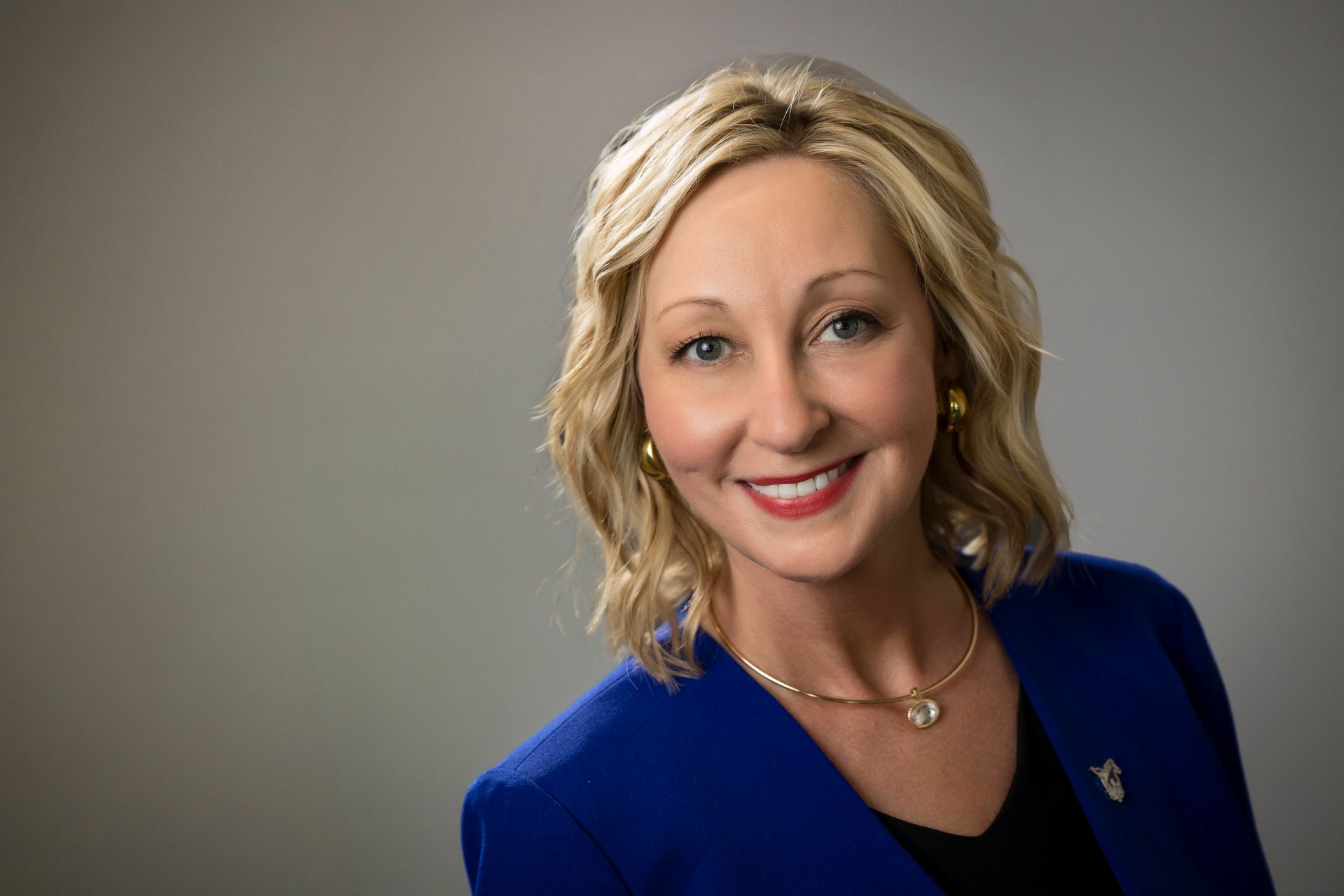 Smiling woman in a blue blazer against a gray background