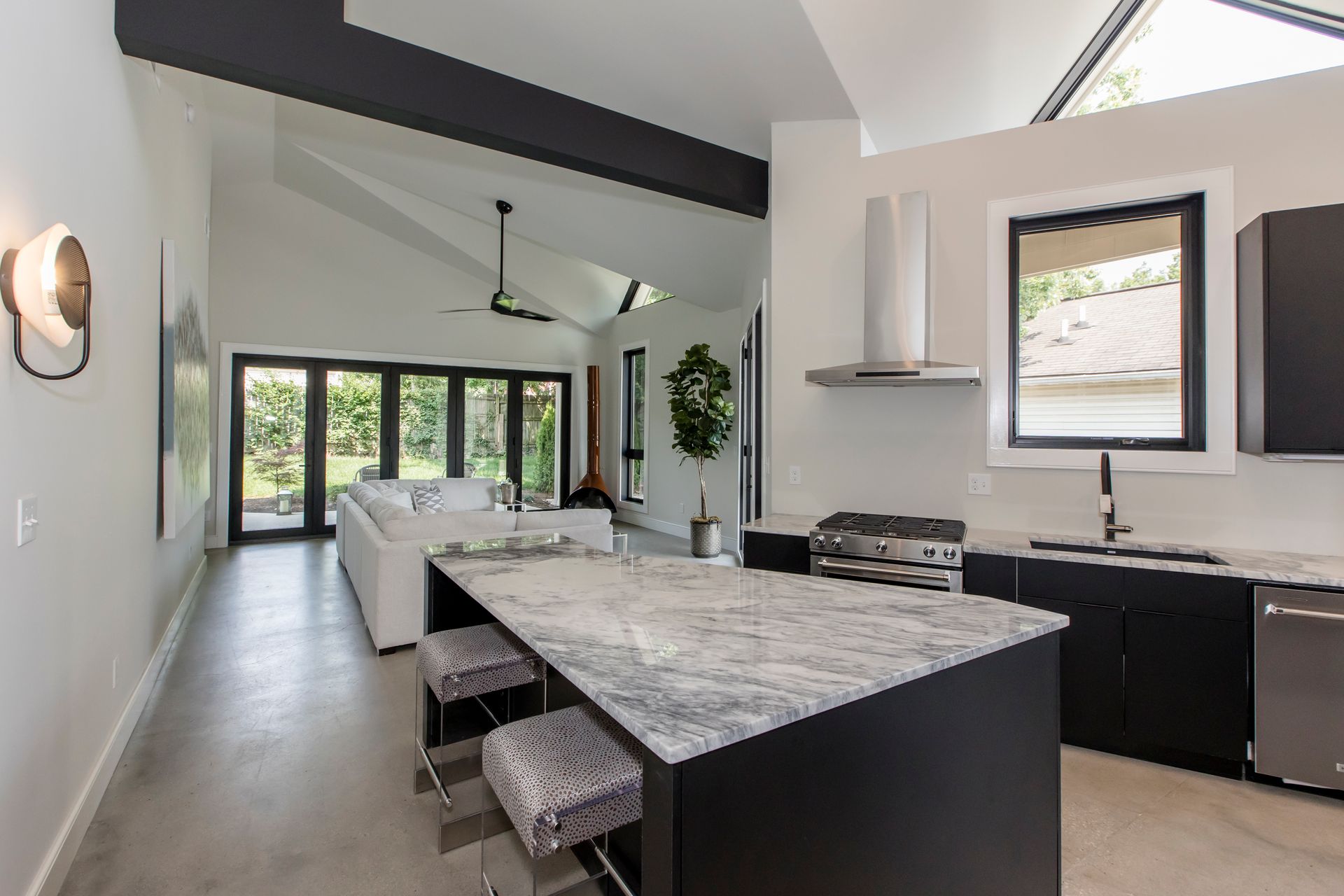 Modern open-concept kitchen and living area with a large island, white sofa, and large windows.