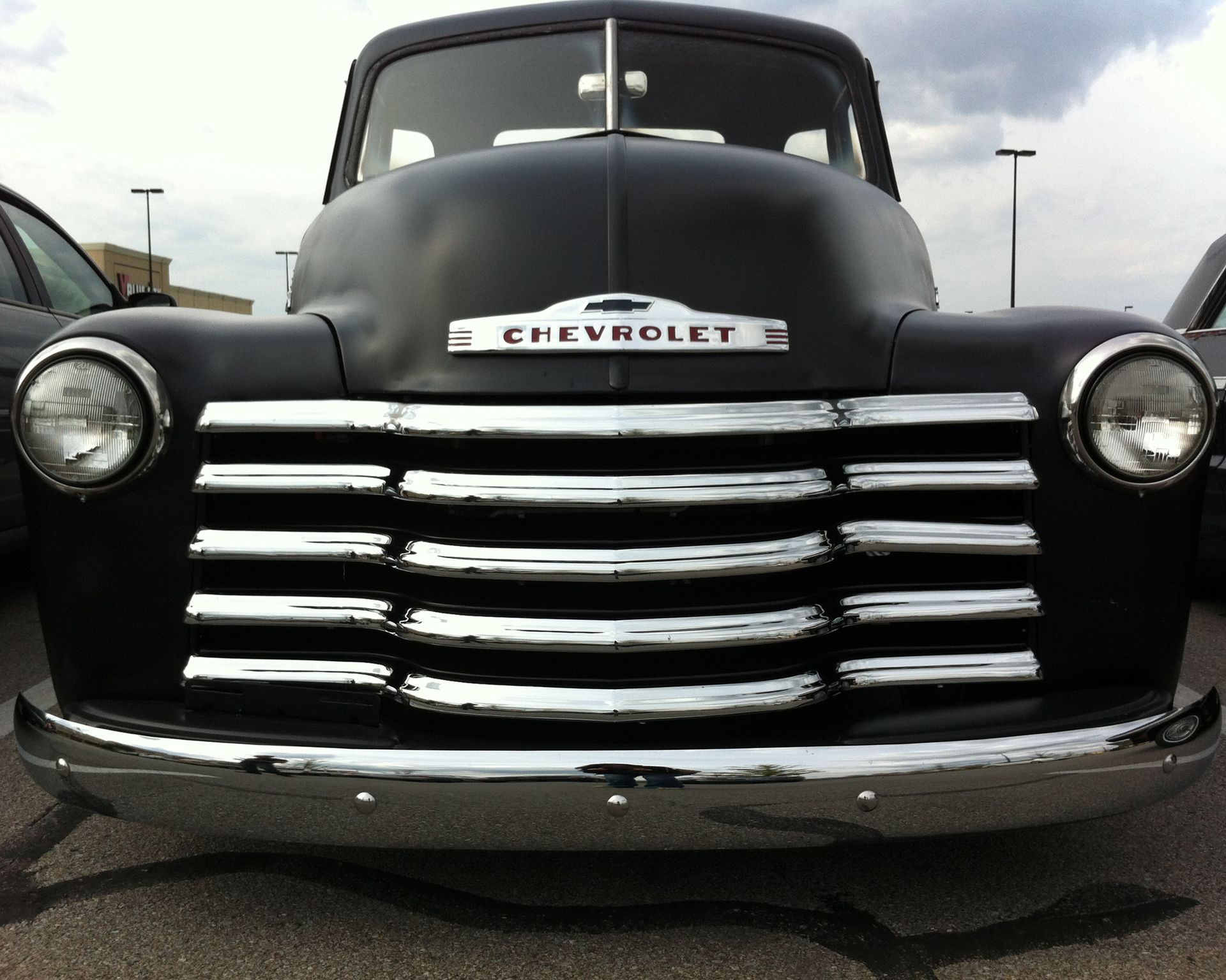 Front view of a black vintage Chevrolet pickup truck with chrome grille and headlights