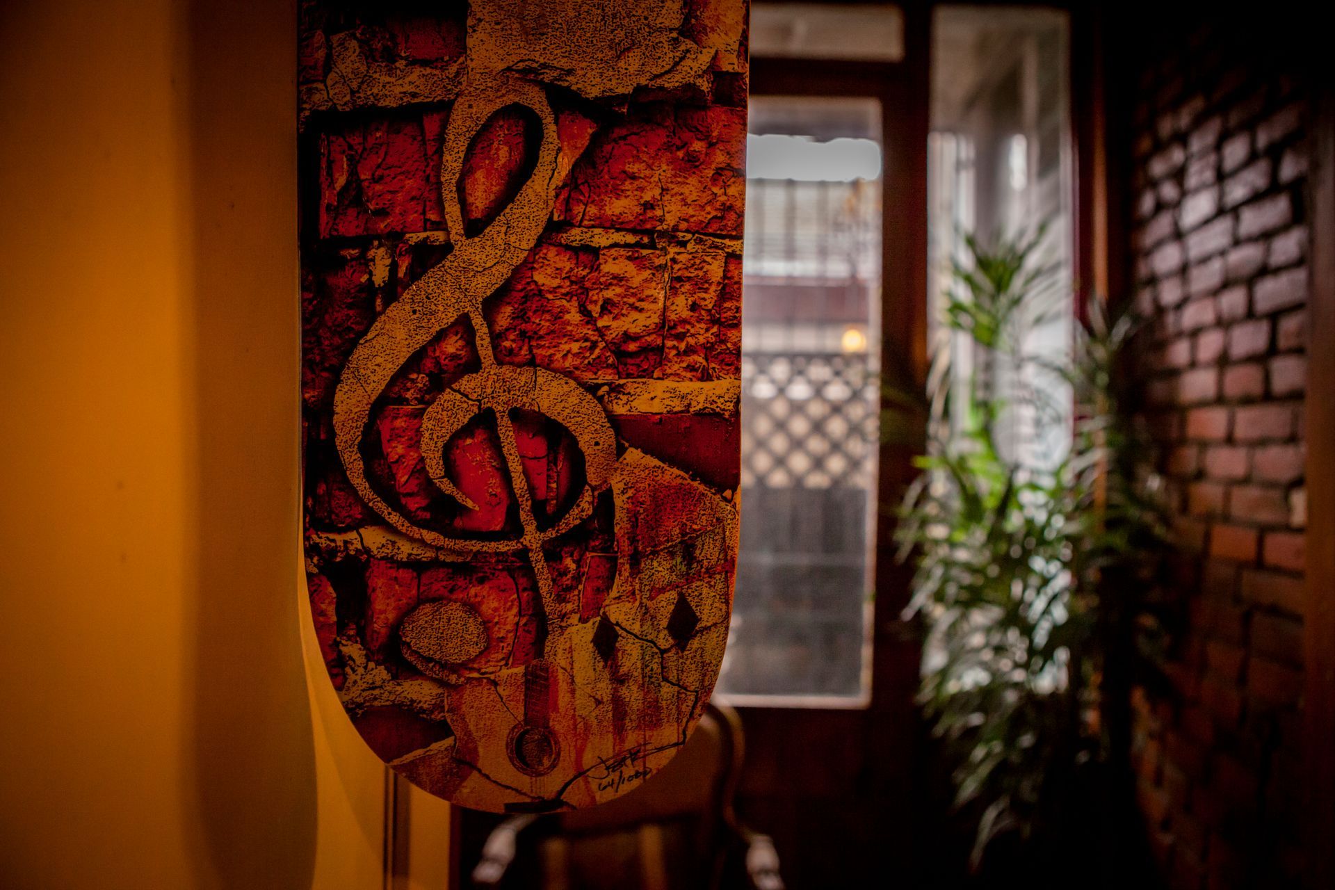 Treble clef mural on an orange wall beside a window and brick wall in a cozy interior