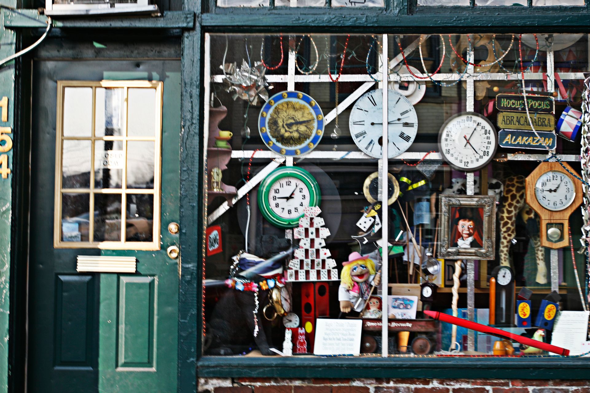 Shop window crowded with clocks and watches beside a dark green door