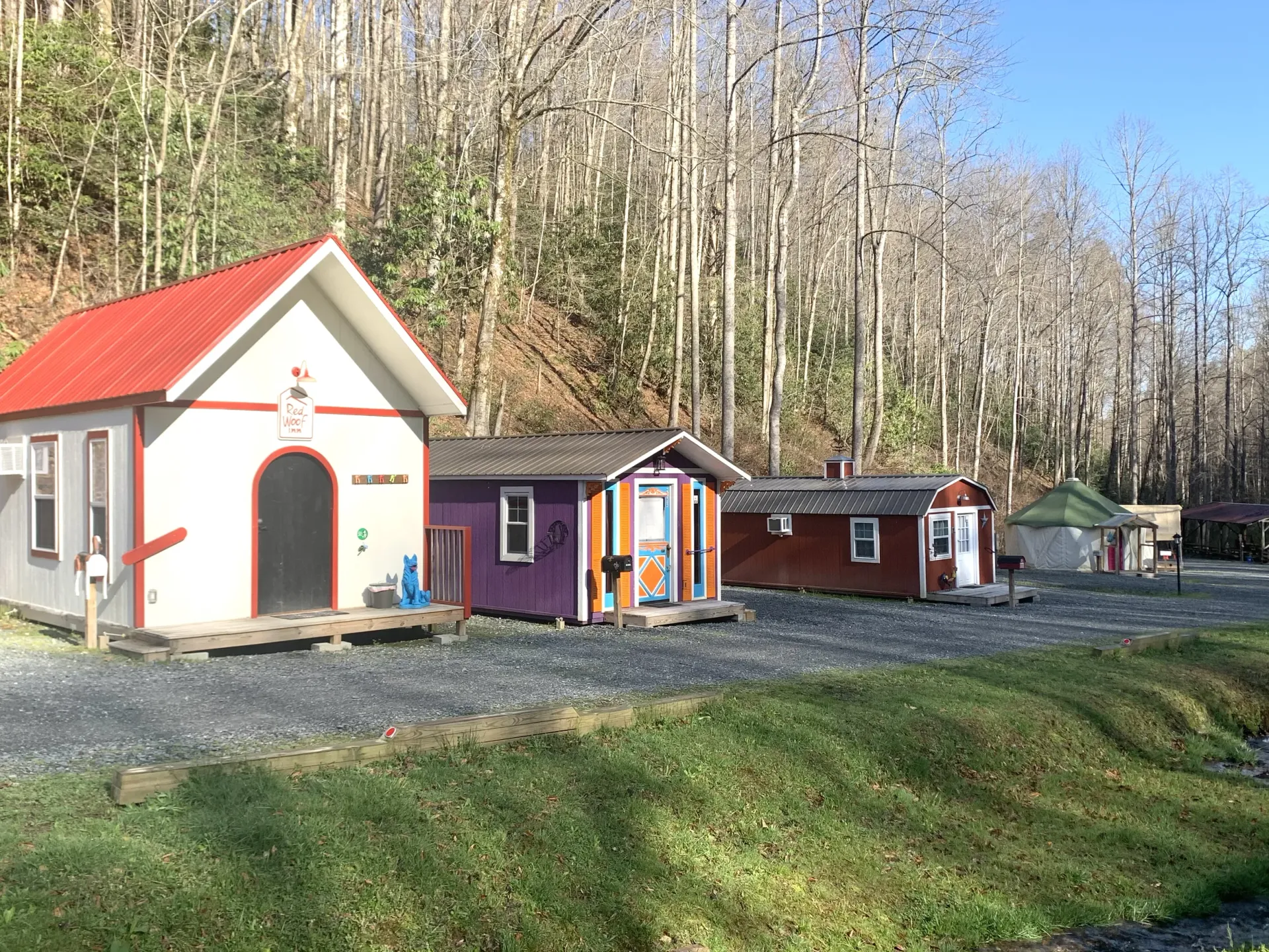 Small colorful cabins along a wooded hillside, with a red-roofed cottage in the foreground.