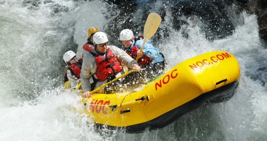 Whitewater rafters in a yellow inflatable raft splashing through rapids