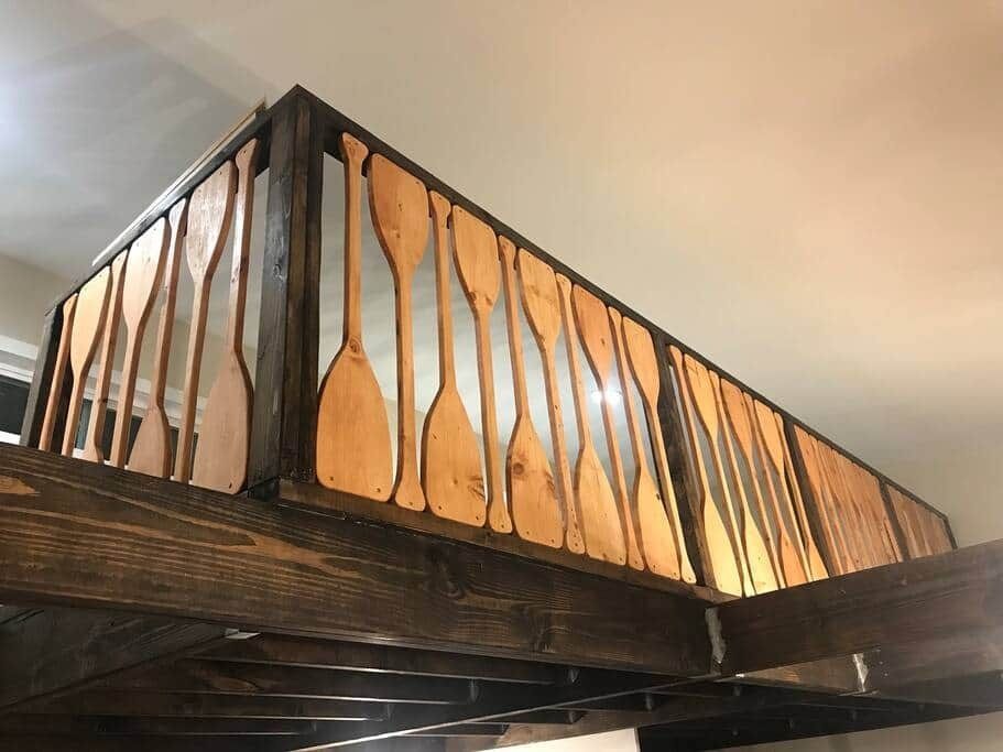 Wooden railing with twisted balusters and dark beams on a loft or balcony ceiling level