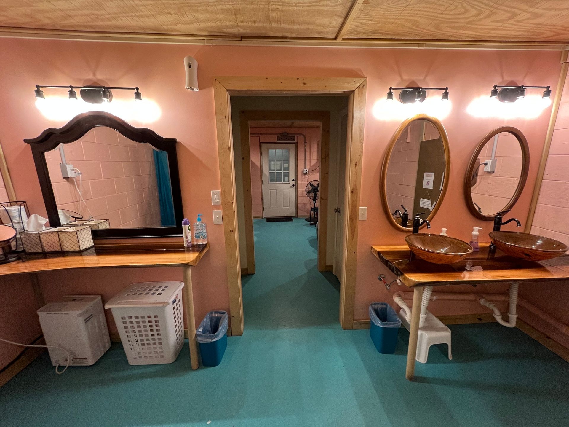 Vintage bathroom with two sinks, oval mirrors, wall lights, and a blue carpeted floor