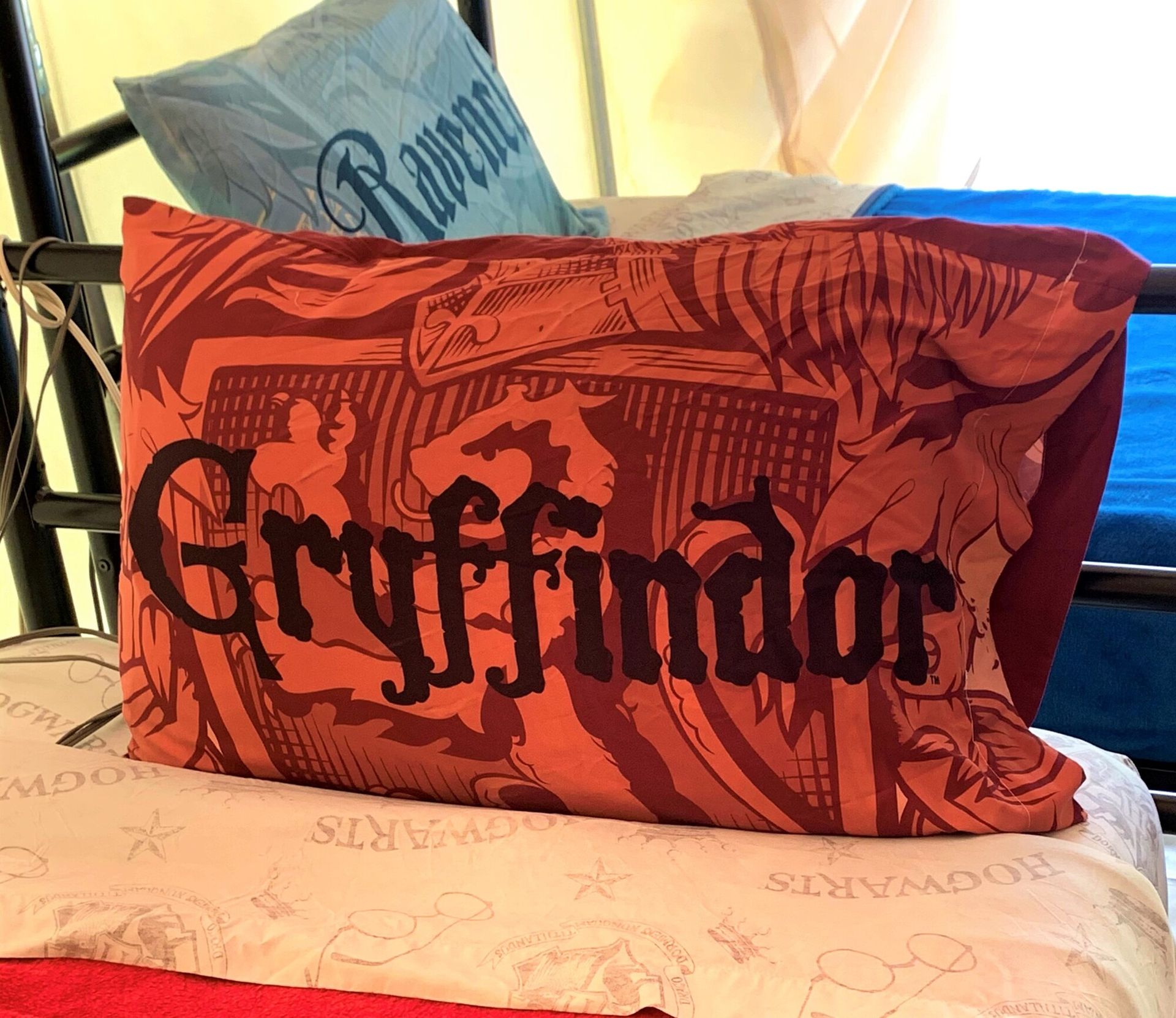 Red Gryffindor pillow on a couch with a light blue pillow behind it