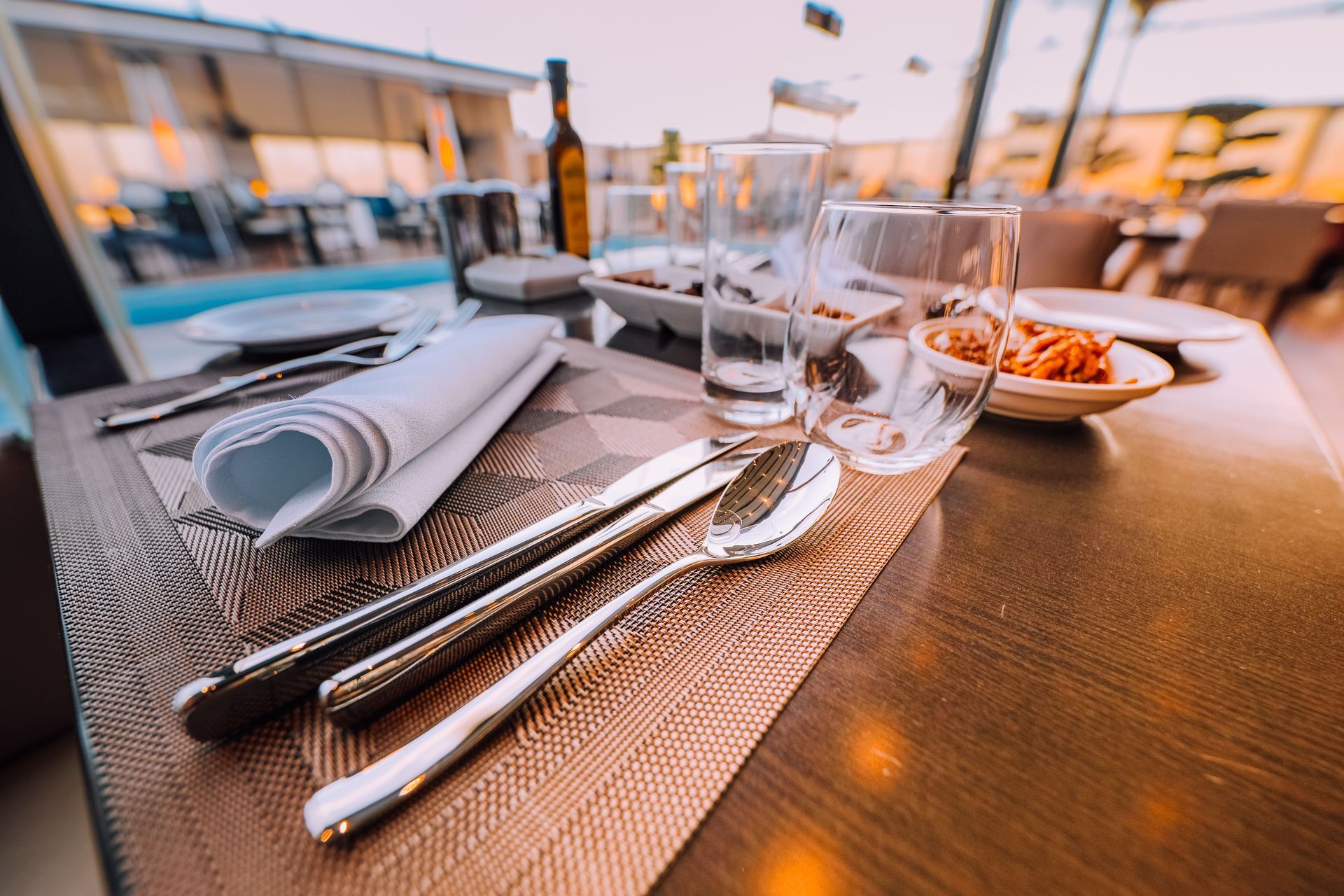 Set dining table with silverware, glasses, and bread basket on a waterfront restaurant terrace