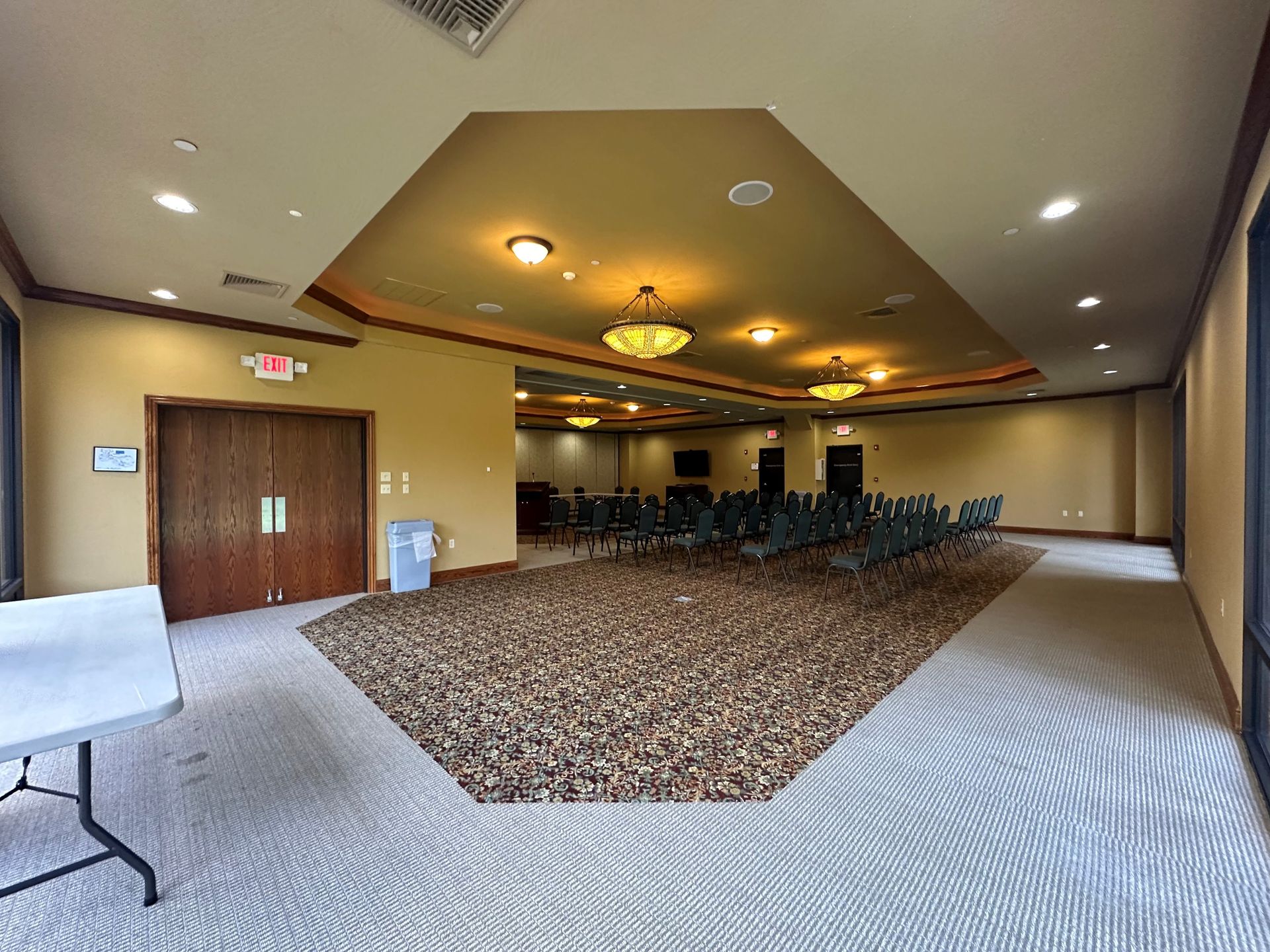 Empty conference room with rows of chairs, beige walls, and carpeted floor