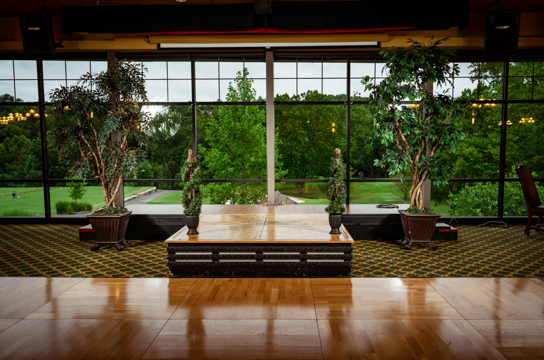 There is a stage in the middle of the room with a view of a park.