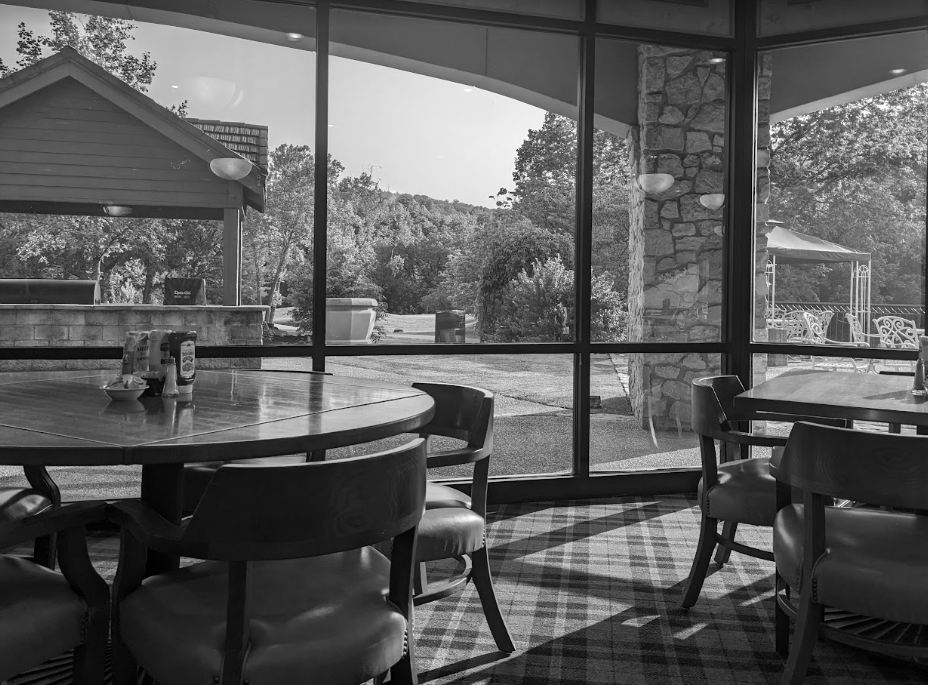 A black and white photo of a restaurant with tables and chairs.