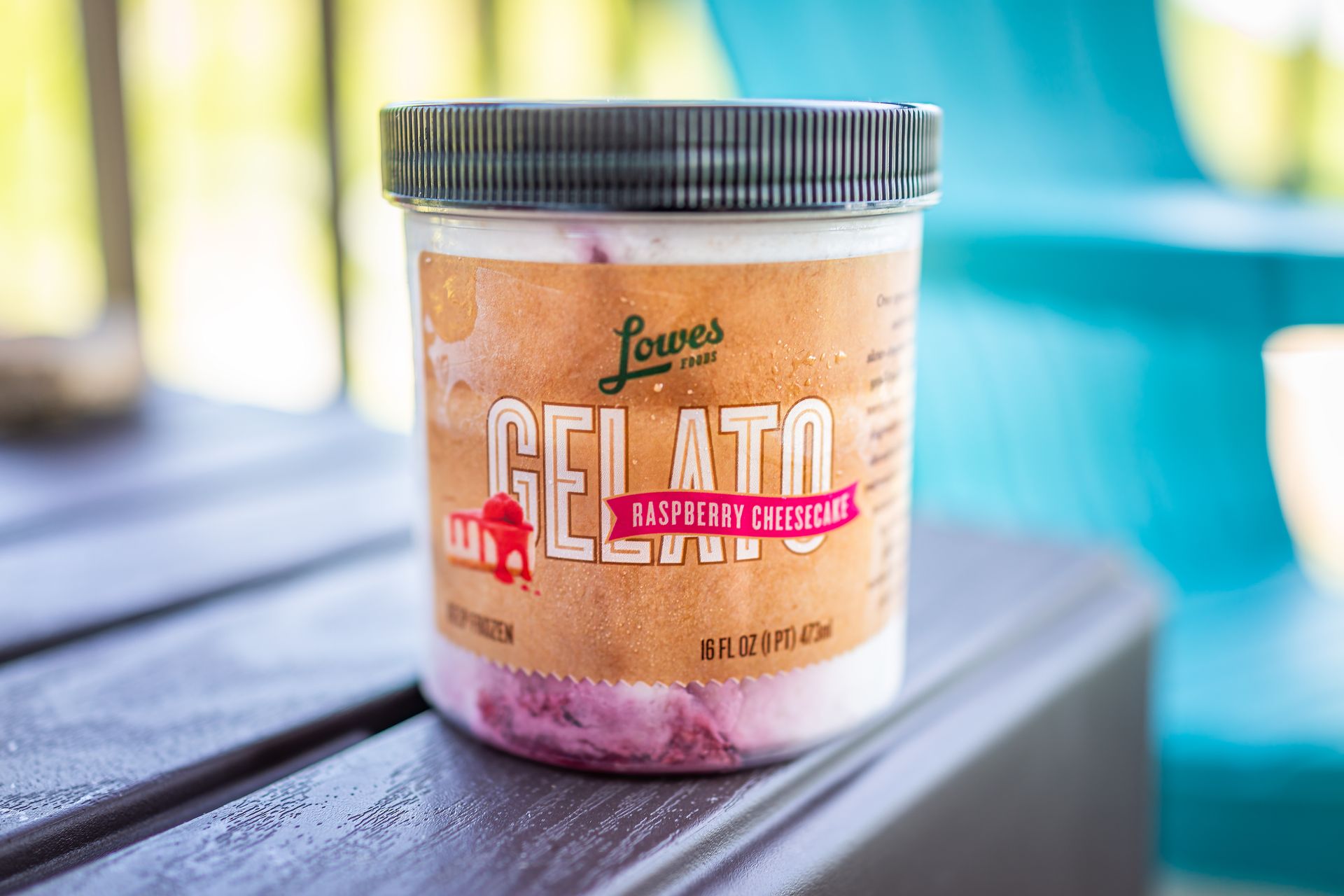 A jar of Louves Raspberry & Chocolate gelato on a wooden table, in an outdoor setting.