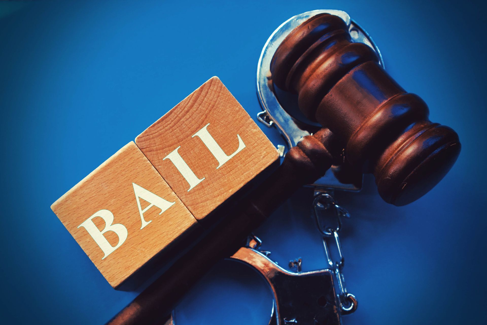 Bail bonds service concept featuring judge gavel, handcuffs, and bail blocks on blue background. Bail bonds service concept featuring judge gavel, handcuffs, and bail blocks on blue background.