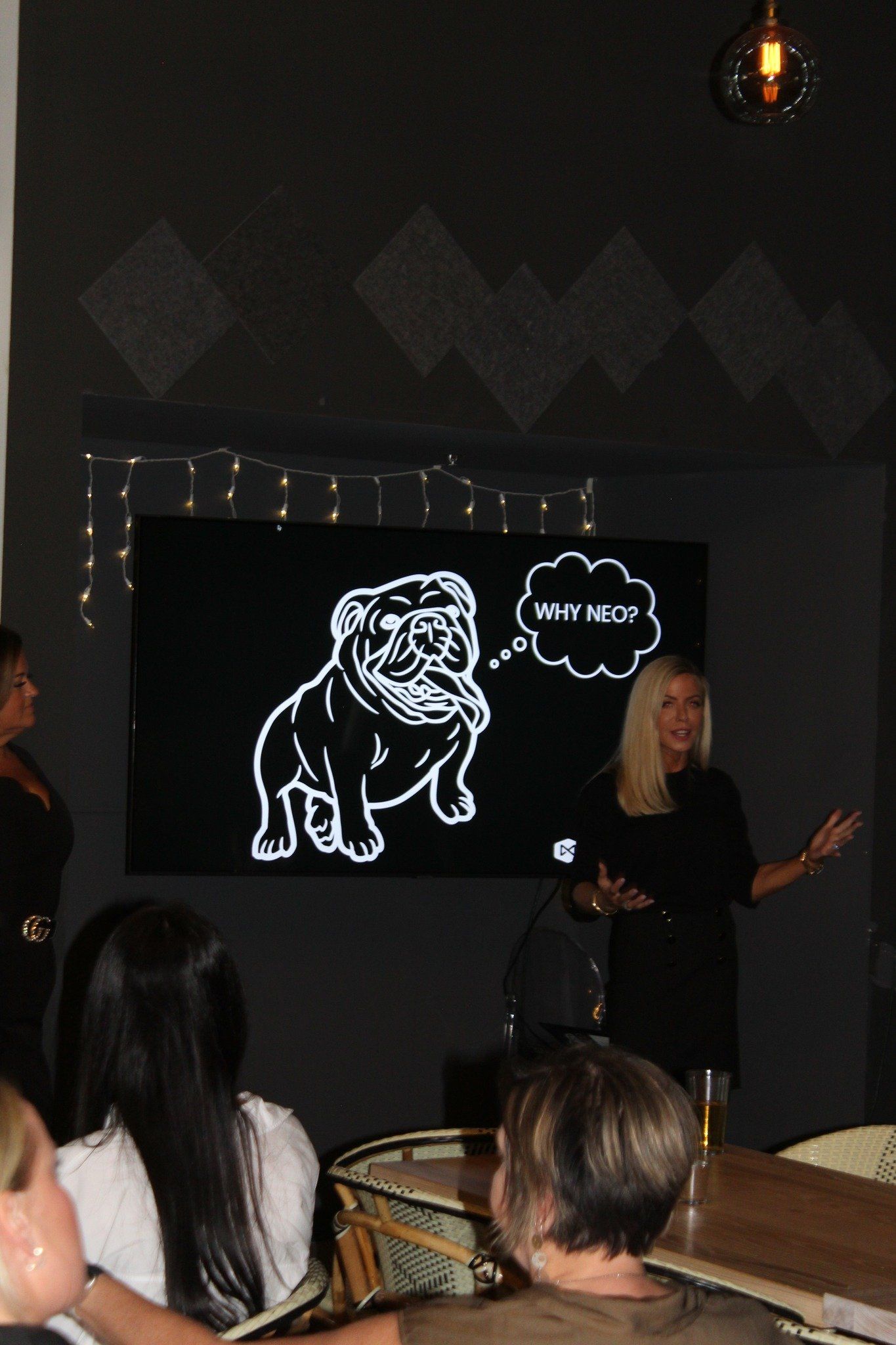 A woman is giving a presentation in front of a screen with a dog on it