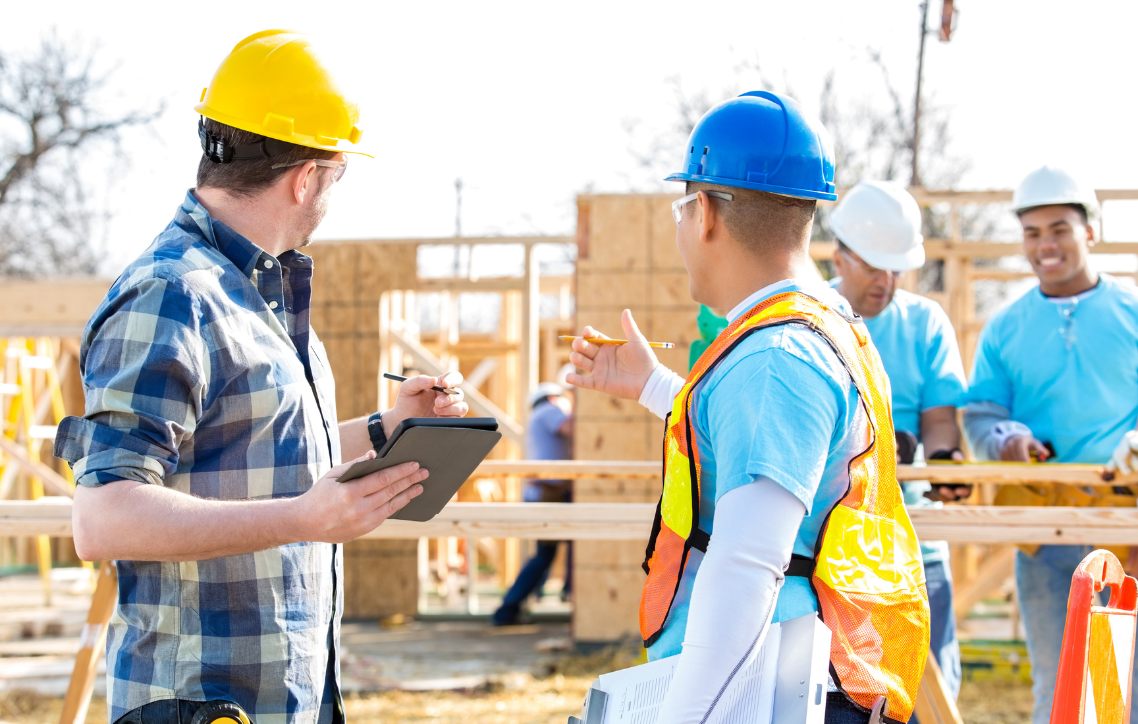 Construction workers in hard hats discussing plans at a building site