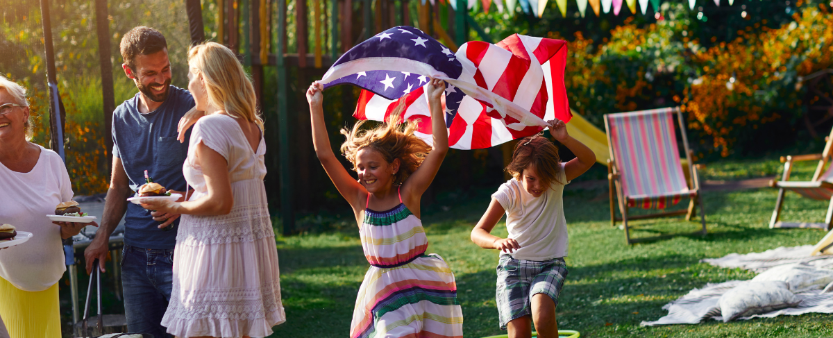 A group of people are standing in a yard holding an american flag.