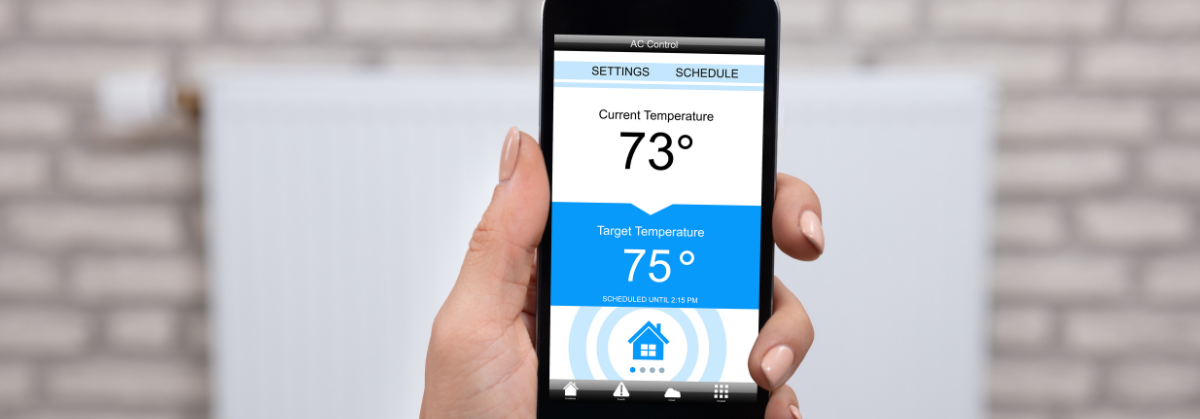 A person is holding a smart phone that shows the temperature is 73 degrees