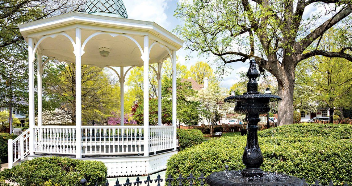 A gazebo in a park with a fountain in front of it
